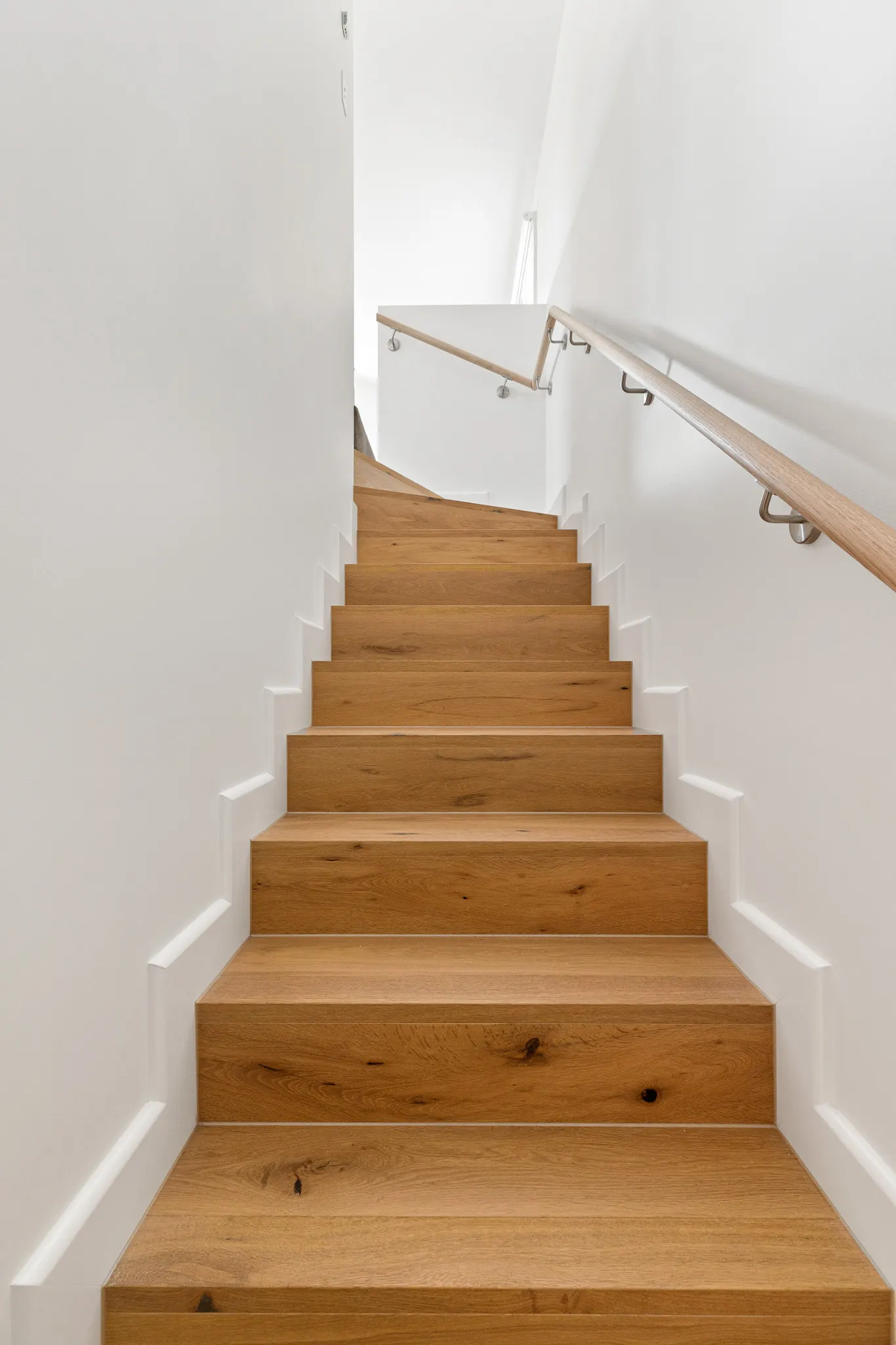 Oak treads and white risers rising to a timber handrail on the stair
