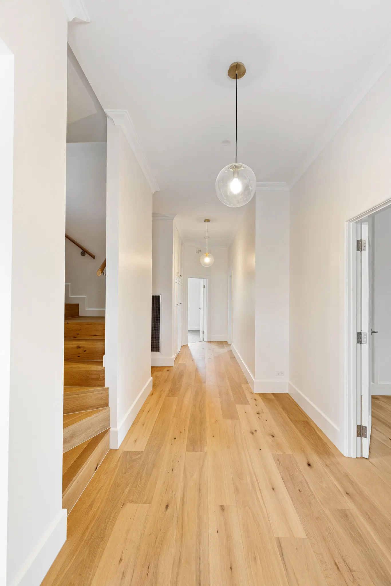 Hallway in oak flooring with glass pendants and the stair opening off to one side