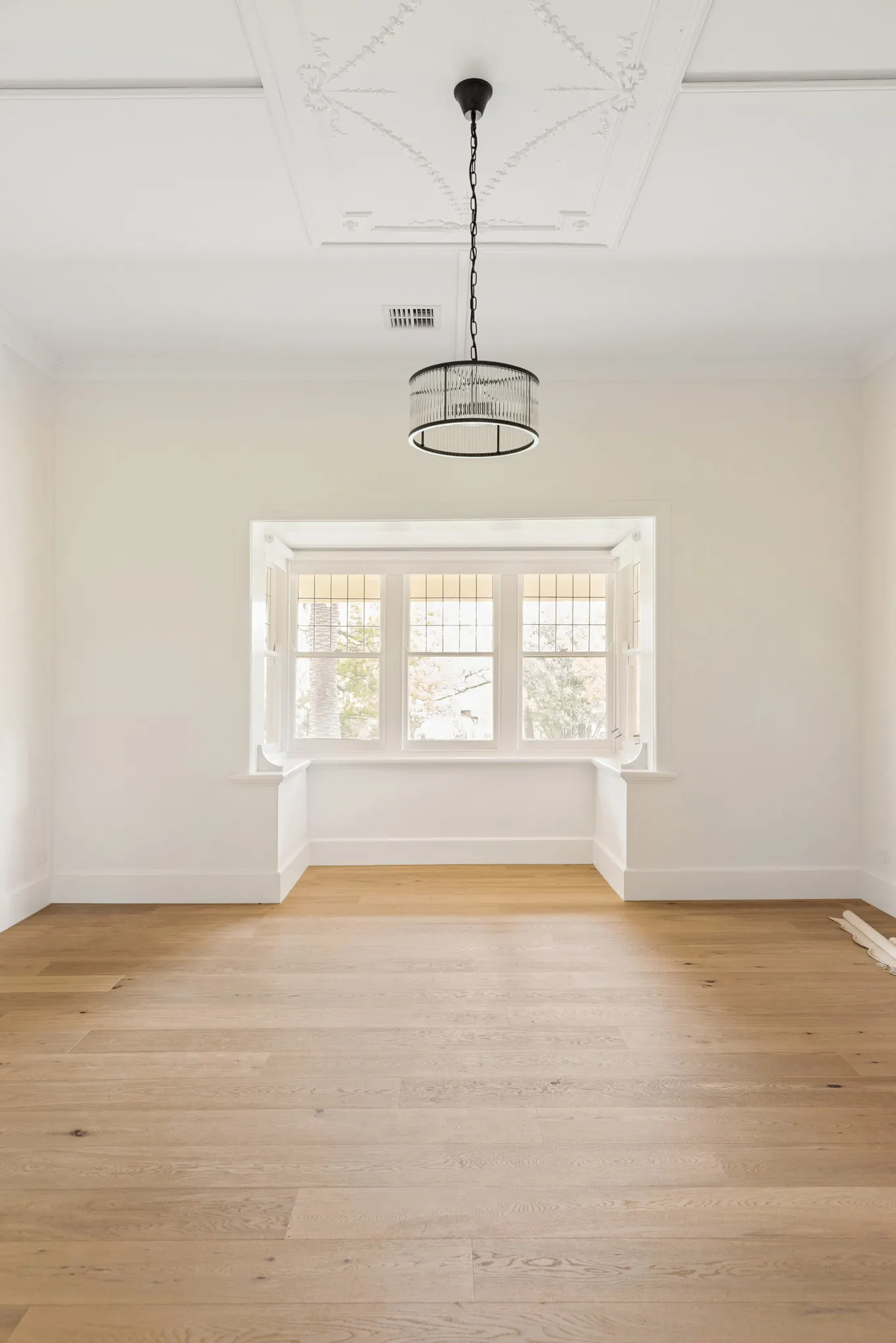 Bay window with a built-in seat below a decorative ceiling and a caged pendant