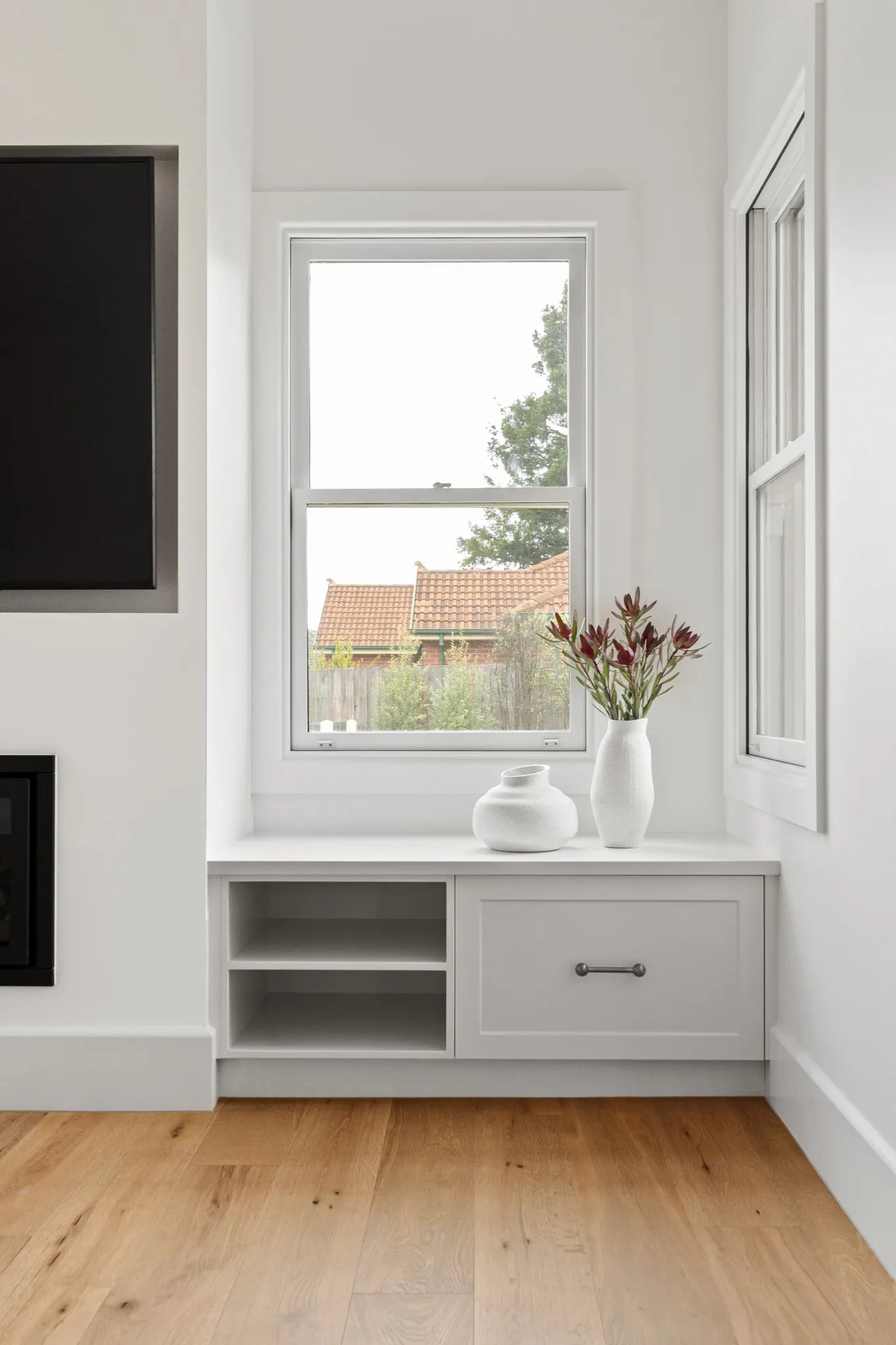 Built-in window seat joinery with open shelving beside a double-hung window