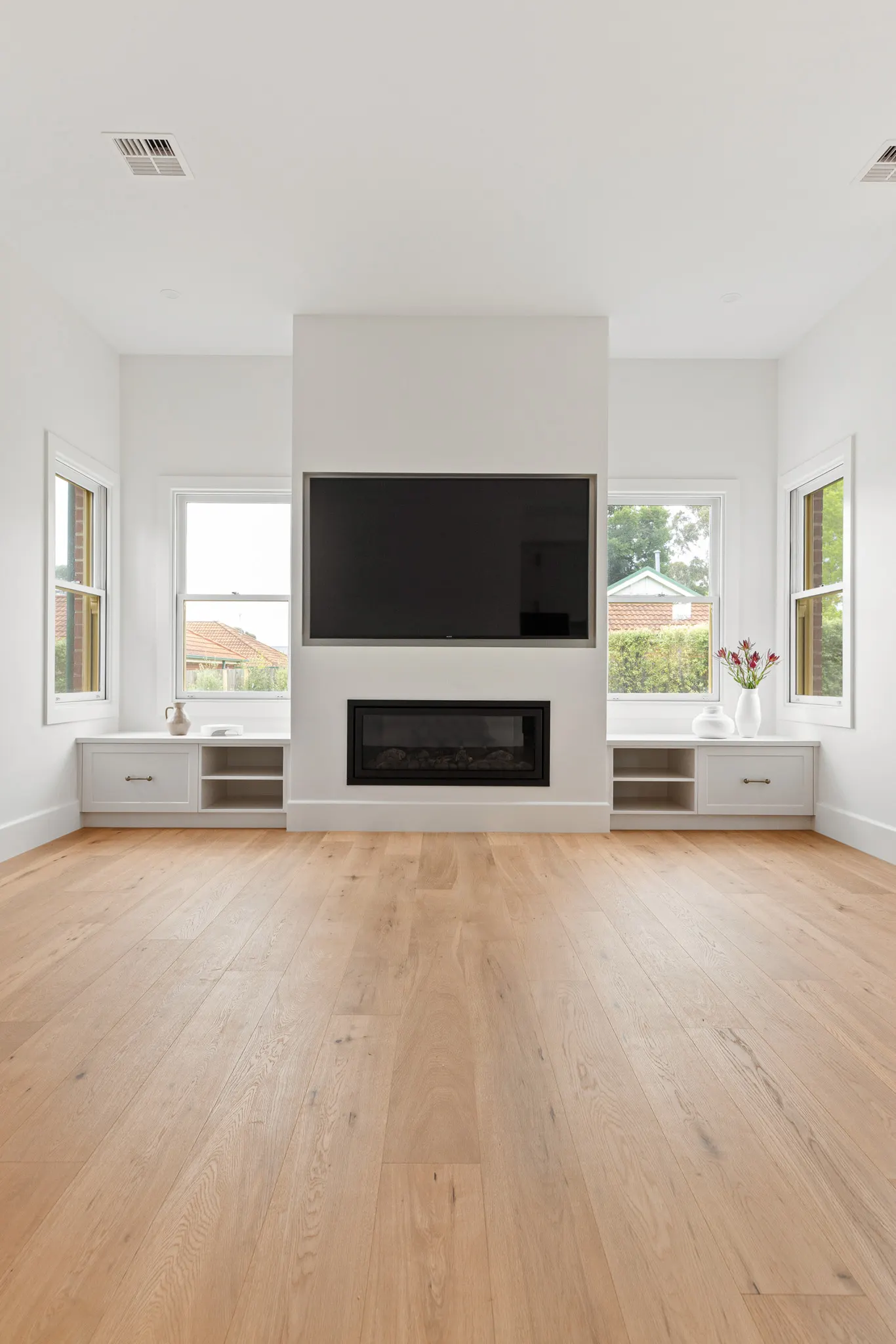 Living room at Barton St with a gas fire below the TV, flanked by window seats