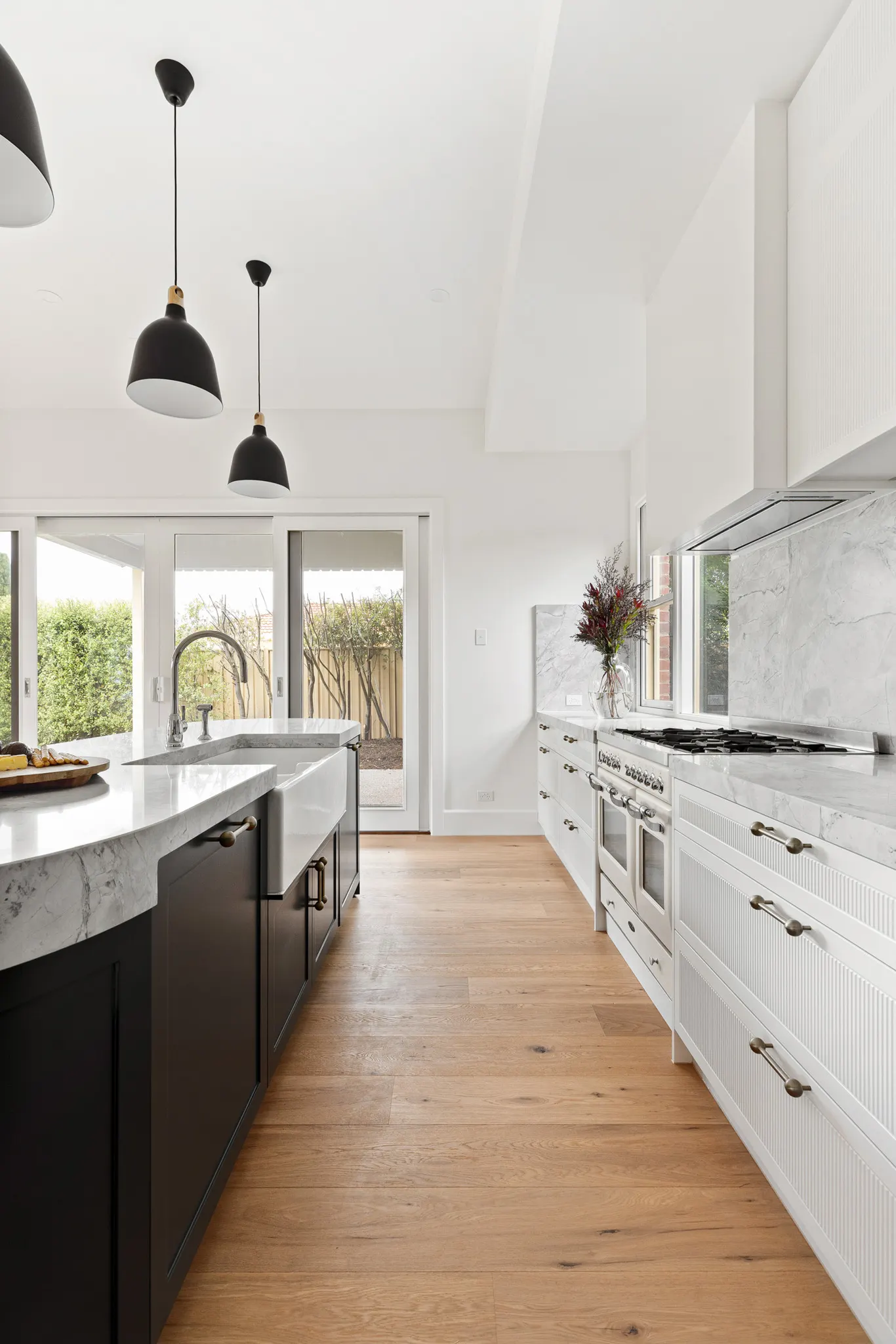 Apron-front sink on the island, freestanding cooker and marble splashback opposite