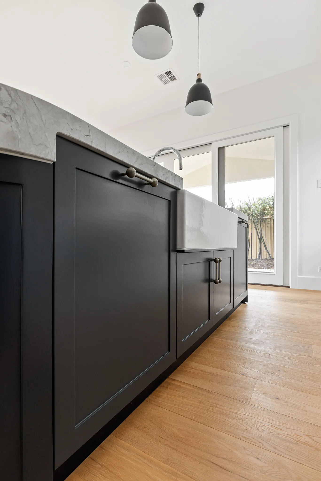 Navy shaker joinery and aged brass handles along the island with its apron sink