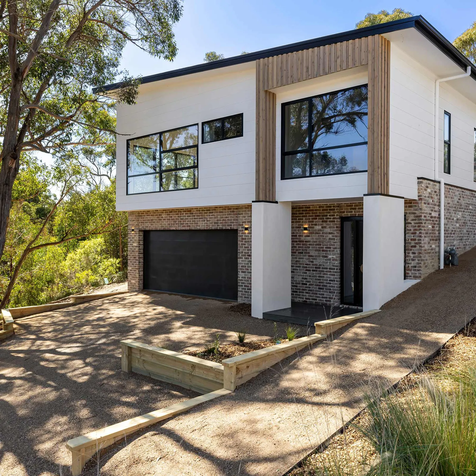 Two-storey facade in white cladding and red brick with timber battens, Dalton St, Gisborne