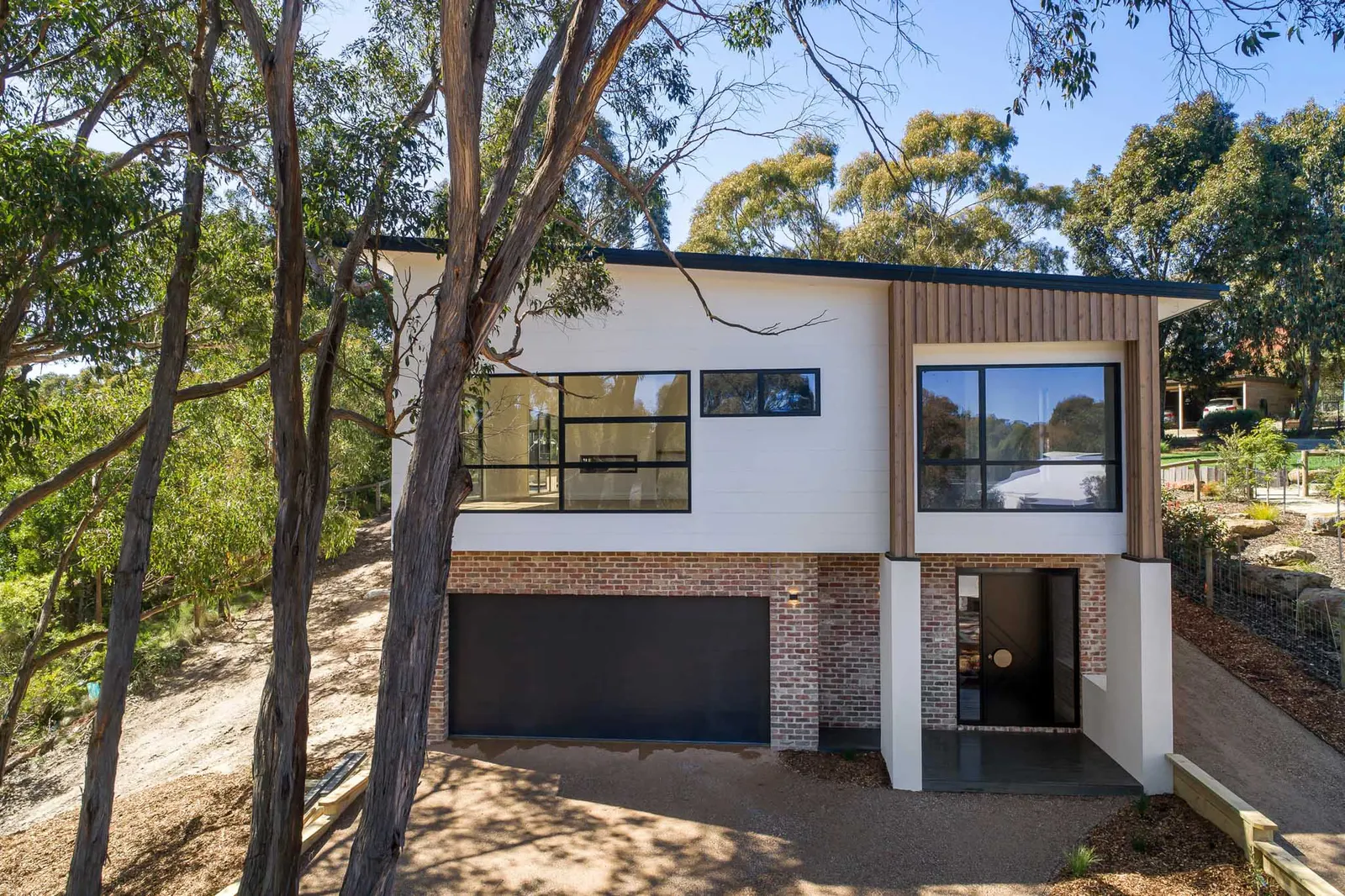 The Dalton St home on its sloping bush block, garage below and gums to the boundary