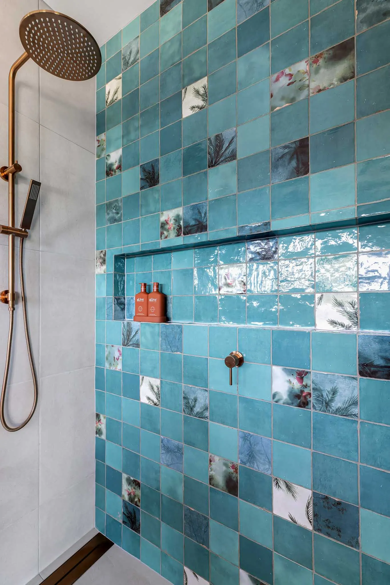 Shower recess in teal gloss tile with patterned inserts, brushed brass rail shower and niche