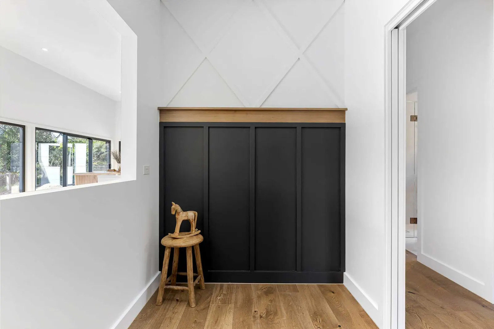 Dark panelled cupboard doors and timber ledge beside a servery opening, oak flooring