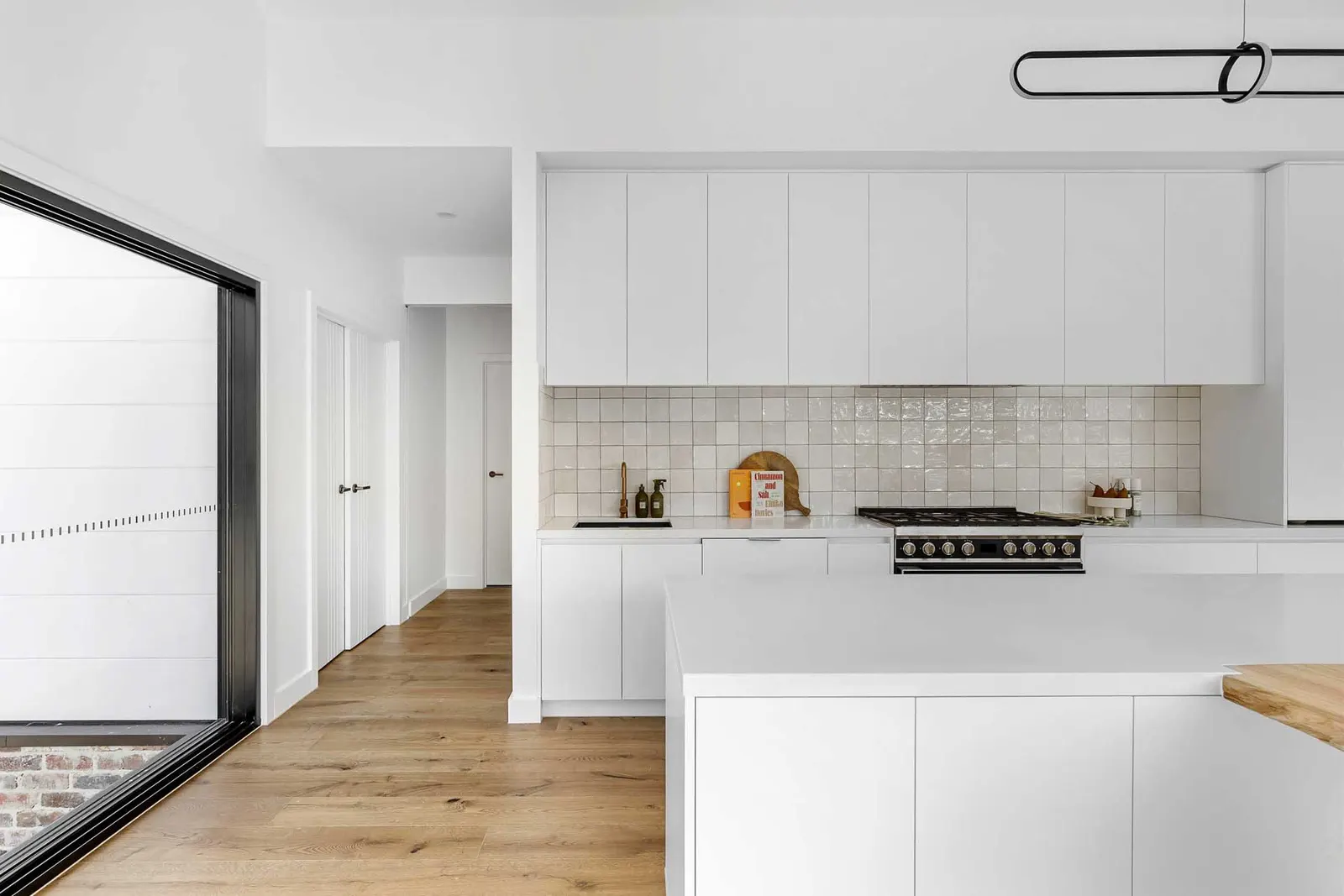 Freestanding cooker below overhead joinery with a cream square tile splashback
