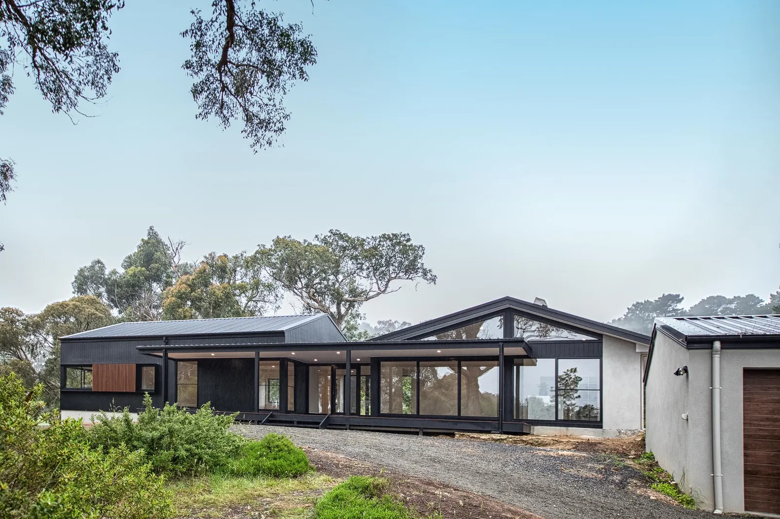 Black-clad Daly St home with skillion roofs and full-height glazing, from the drive