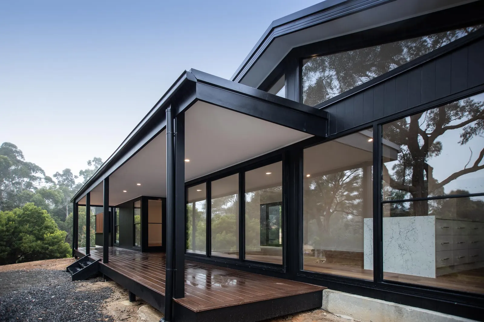 Corner of the veranda where full-height glazing meets the deck and black steel posts