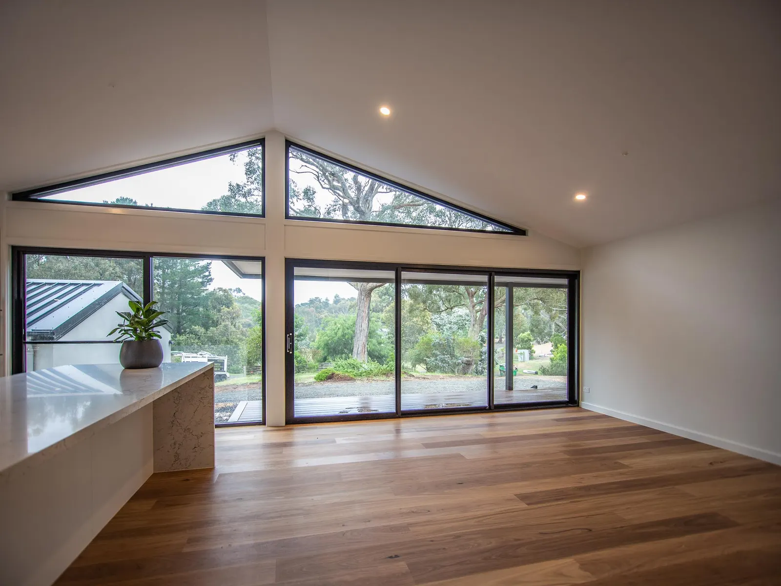 Living room with a raked ceiling, triangular gable window and sliding doors to the deck