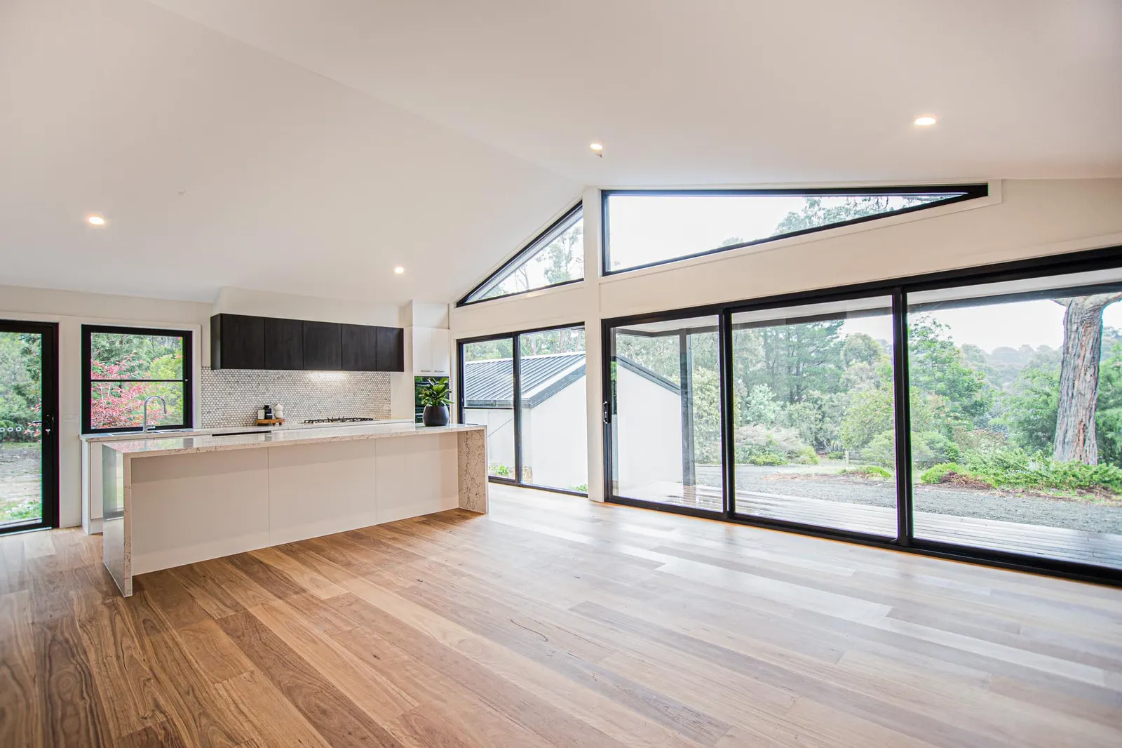Open plan living and kitchen at Daly St, with oak floors and a raked ceiling above