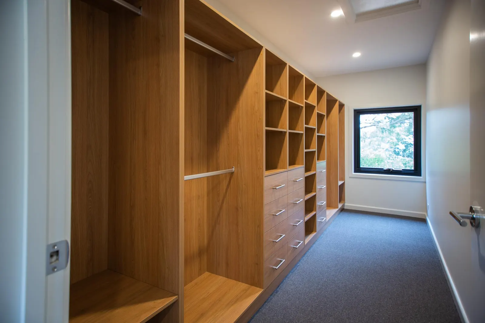 Walk-in robe in timber joinery with hanging rails, drawers and open shelving