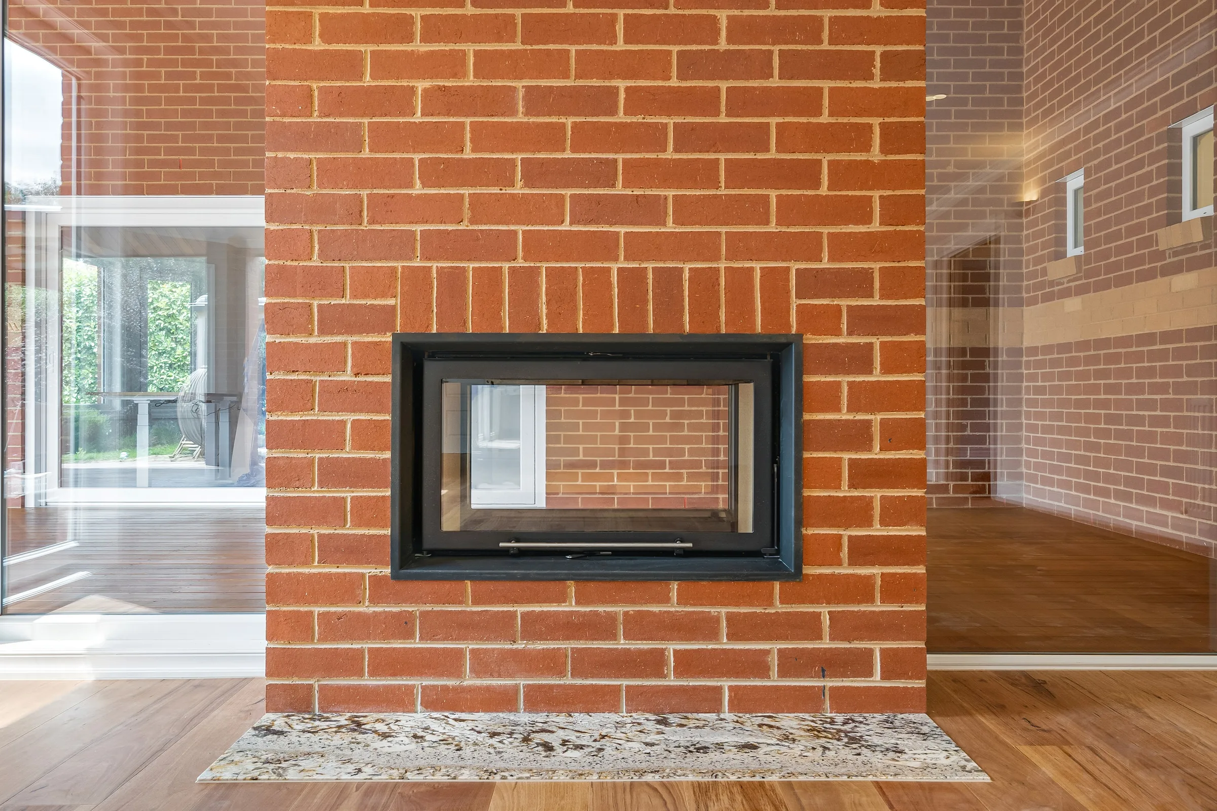 Face-on view of the double-sided fireplace, red brickwork framing the glass firebox
