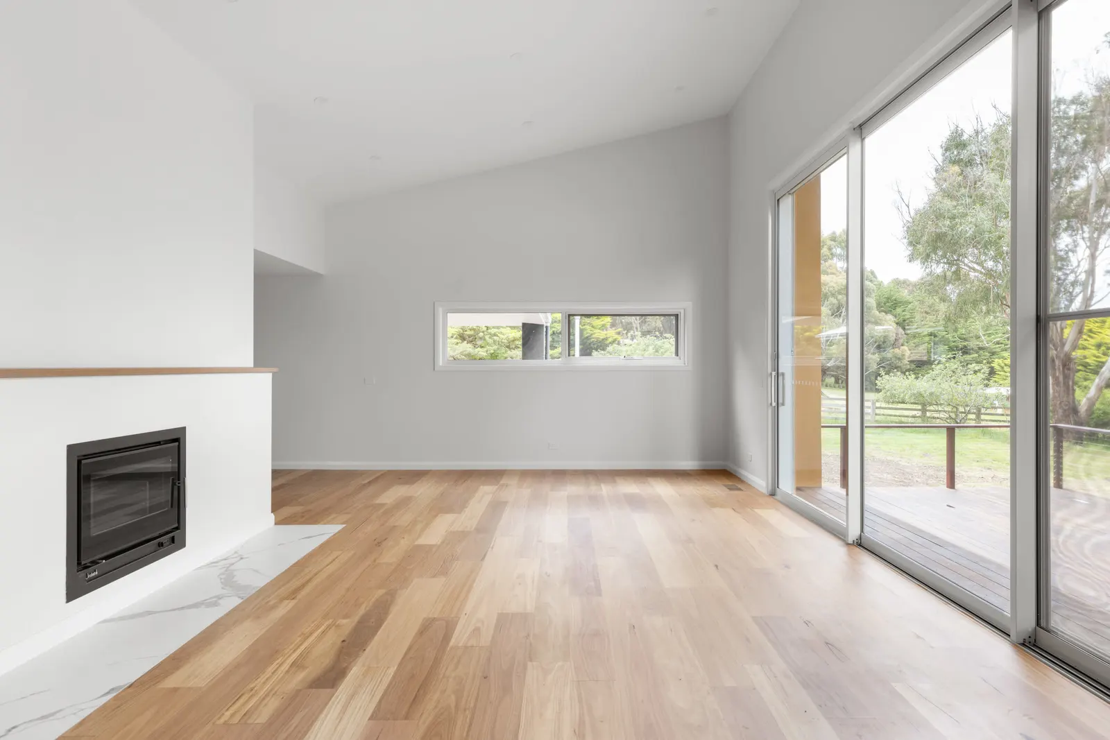 Corner glazing and a highlight window in the living room, fireplace and oak floors to the left