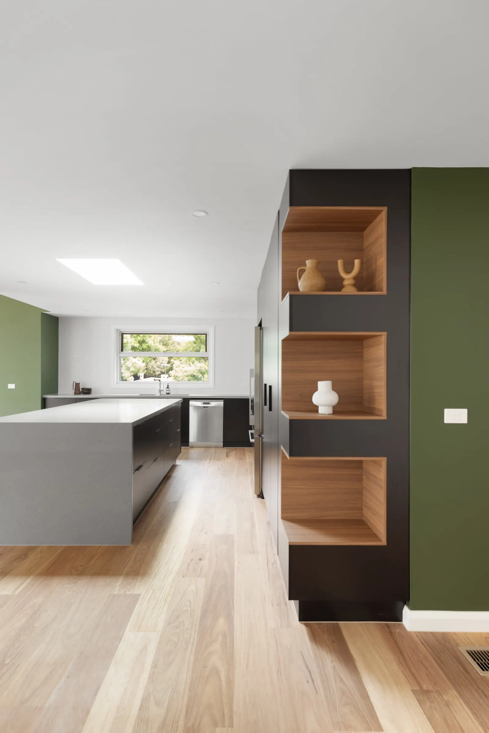 Three timber-lined niches in the black joinery column, window over the sink behind