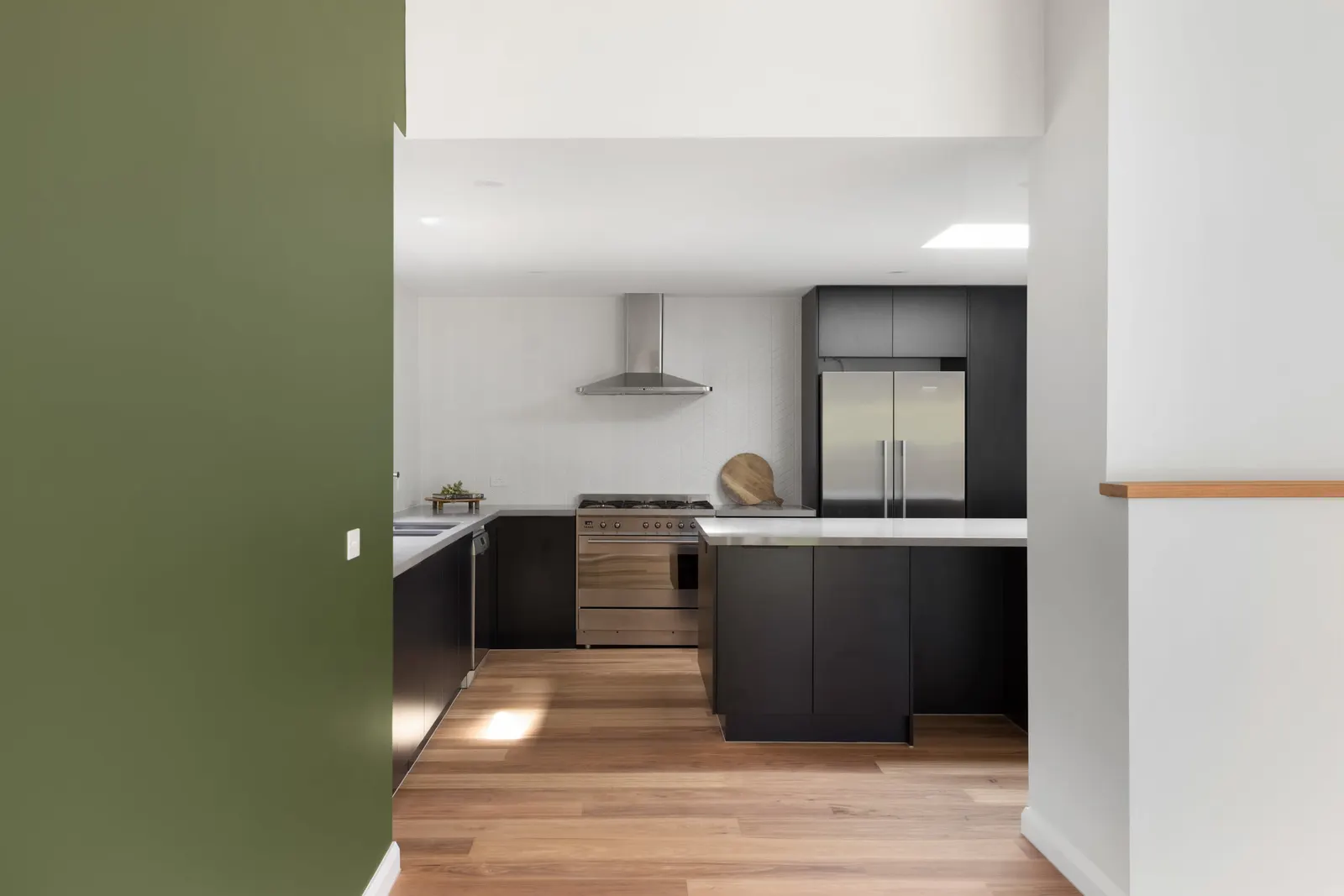 Kitchen from the hallway with black joinery, a stainless freestanding cooker and canopy rangehood