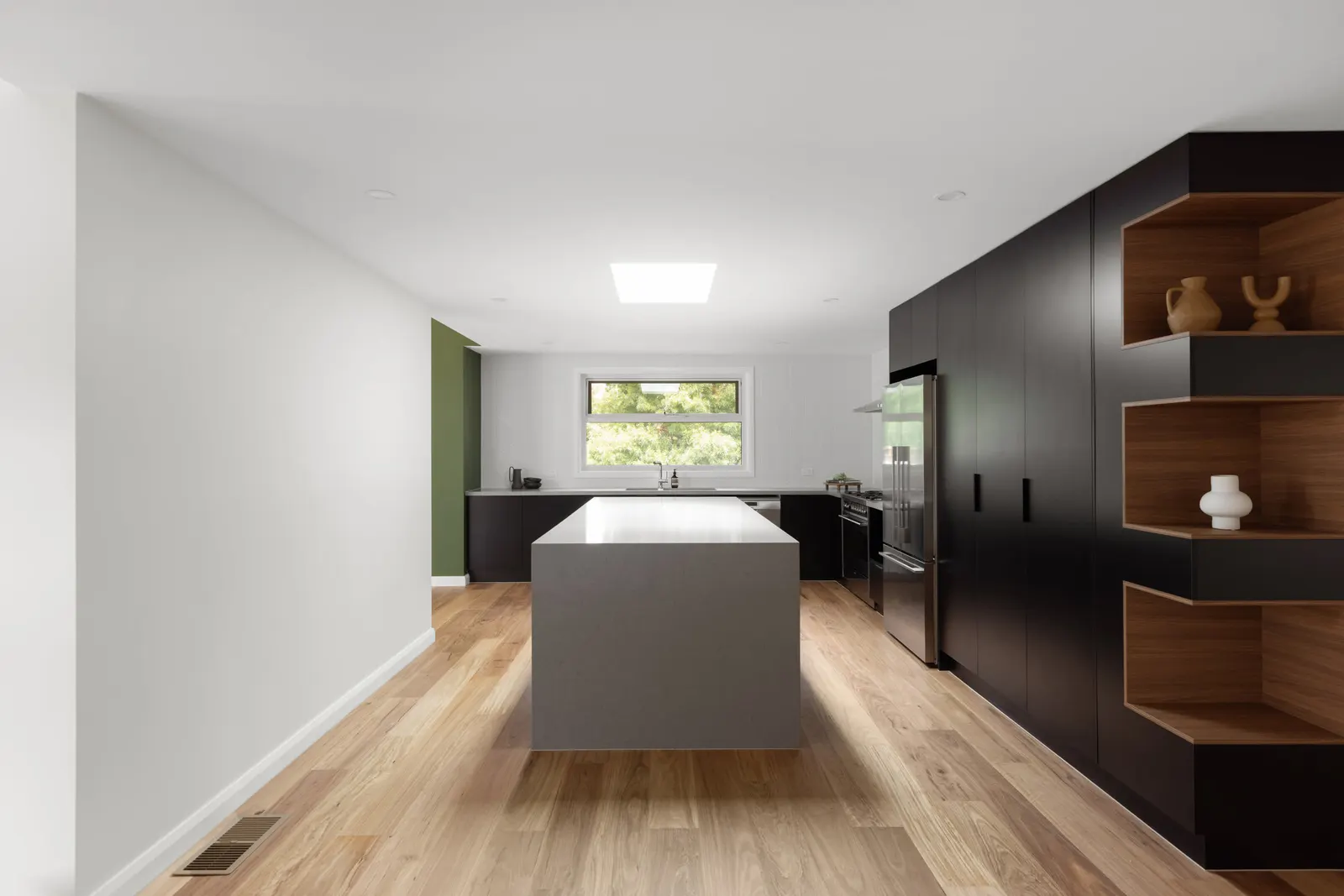 Open kitchen at High View Crescent with a grey stone island, black joinery and oak flooring
