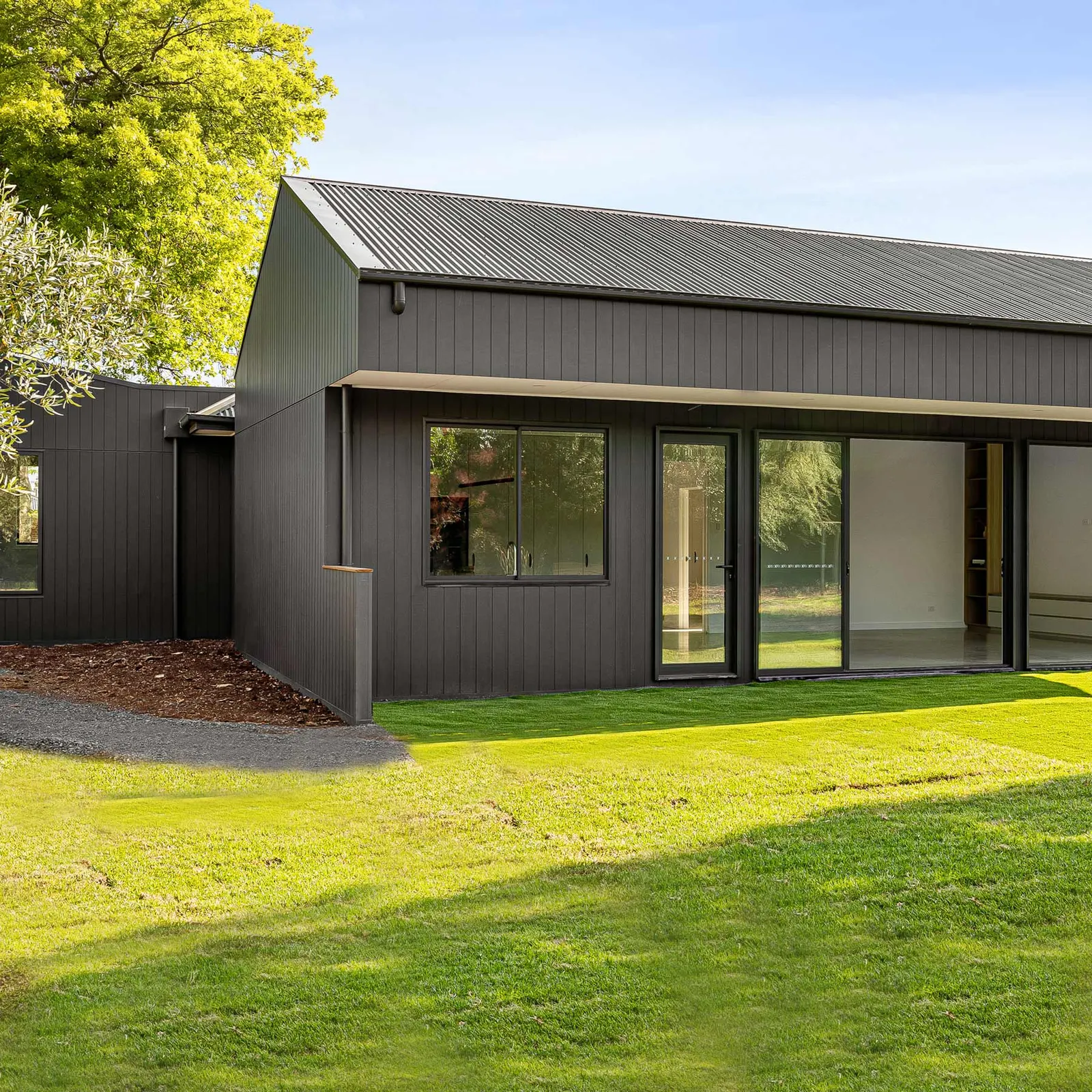 Rear elevation of the Manor in the Macedon Ranges, dark vertical cladding facing the lawn