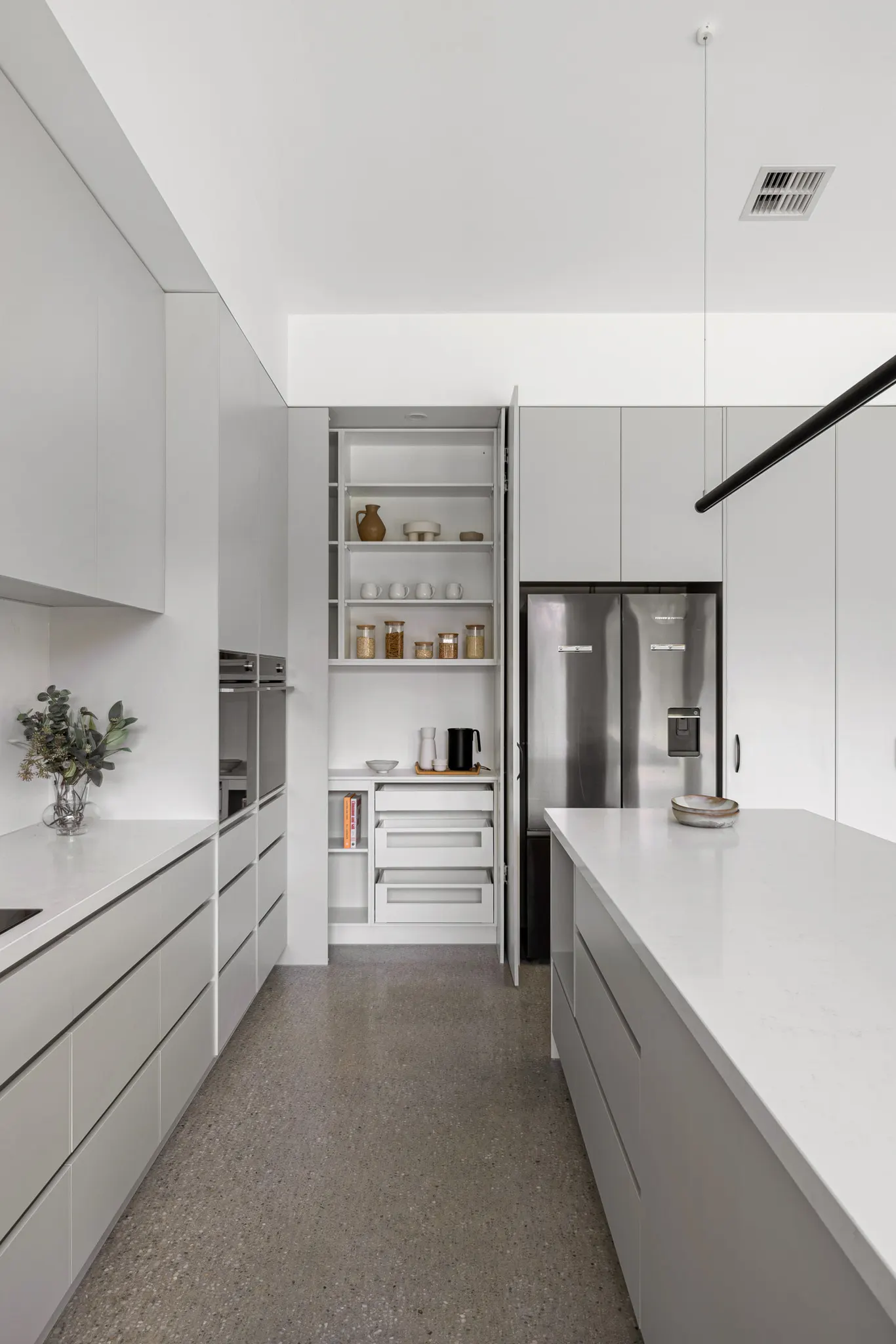 Galley kitchen run with an open pantry cupboard, deep drawers and a stainless steel fridge