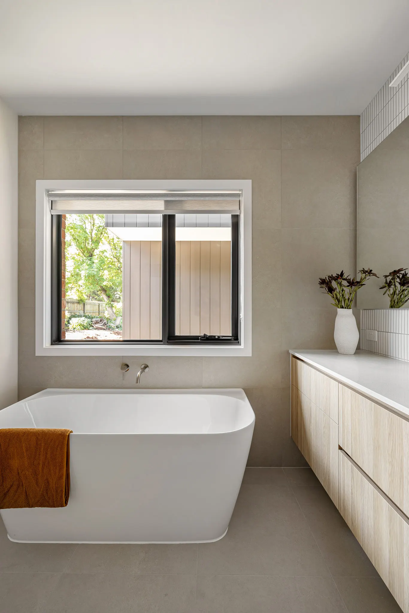 Bath set below a garden window with a wall-hung timber vanity alongside