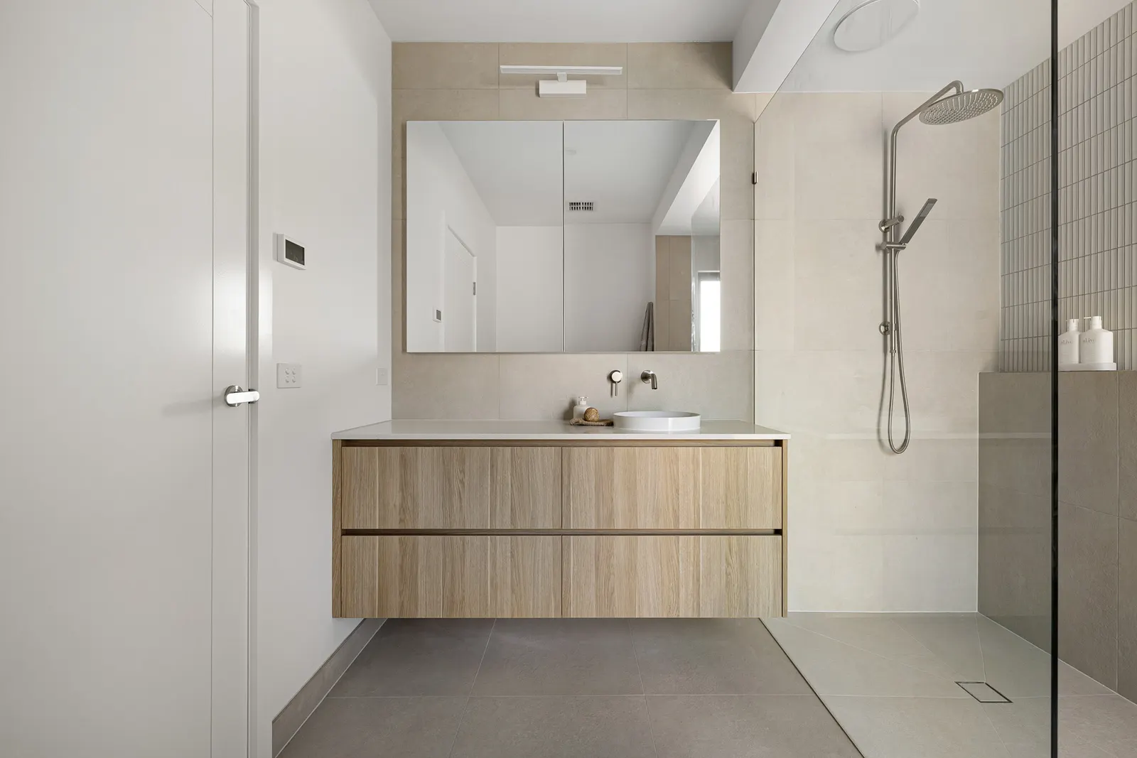 Wide bathroom view with a full-width mirror, timber vanity and open shower