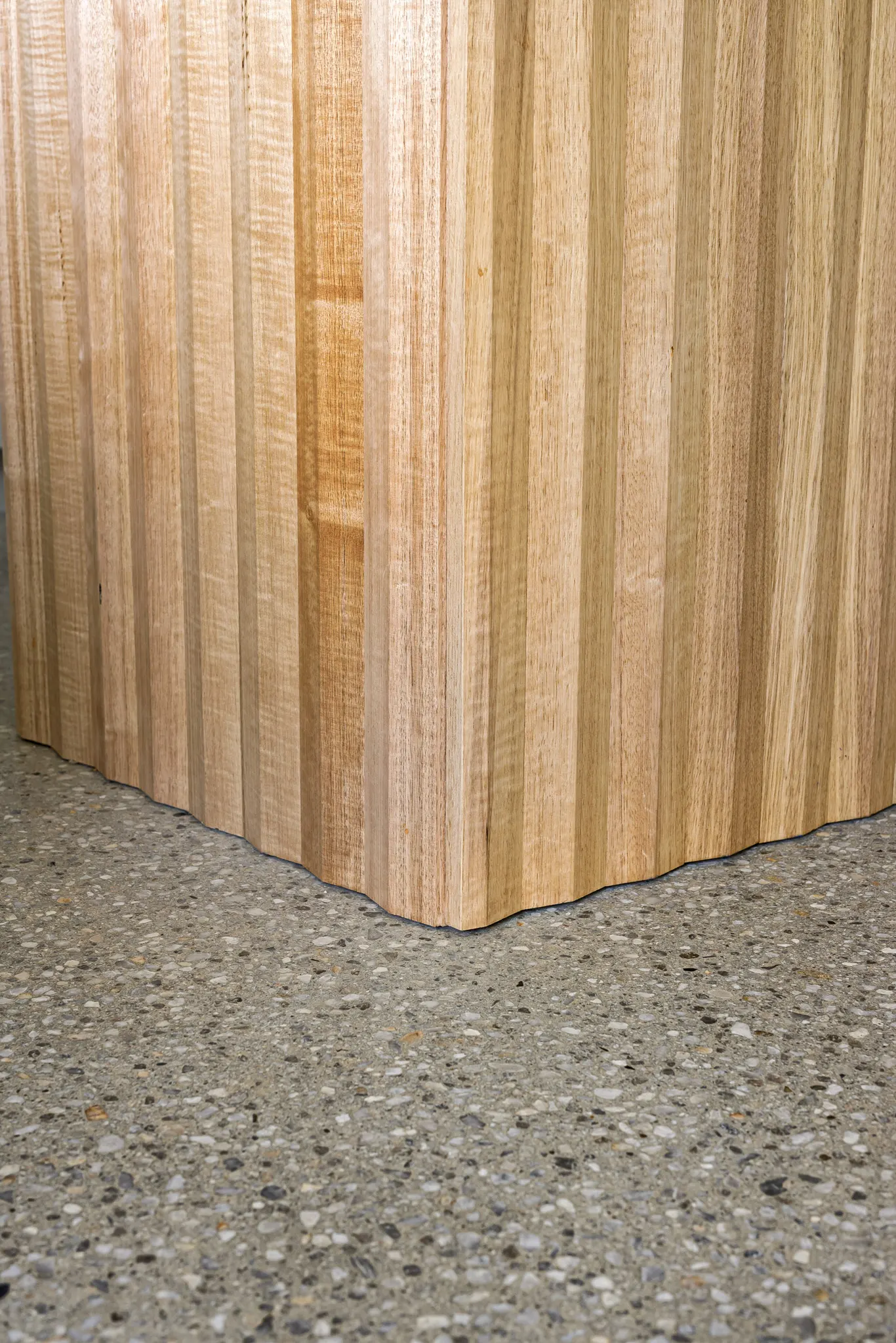 Close detail of the fluted timber island base against the polished concrete floor