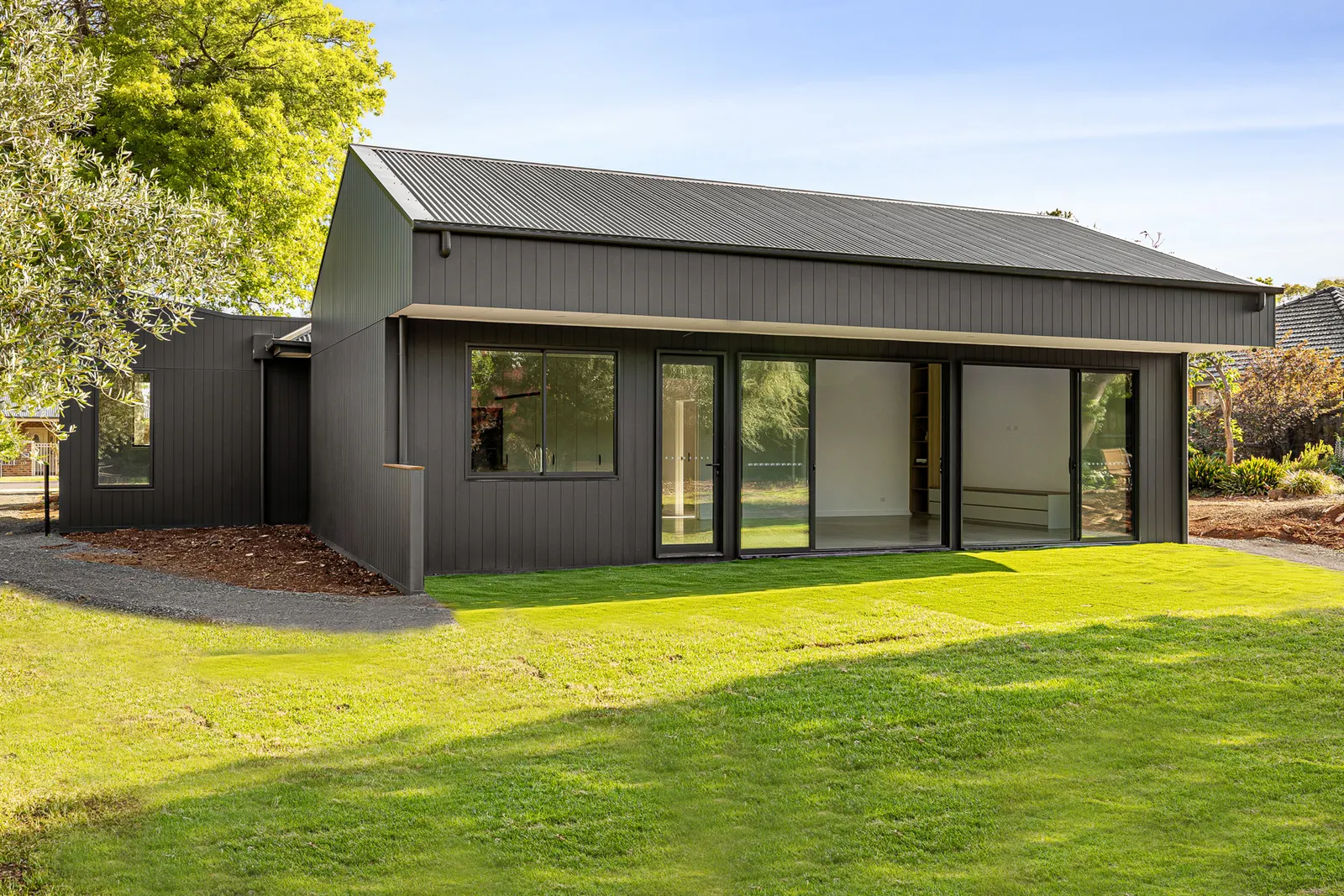 Three-quarter view of the finished Manor home, lawn running up to the sliding doors