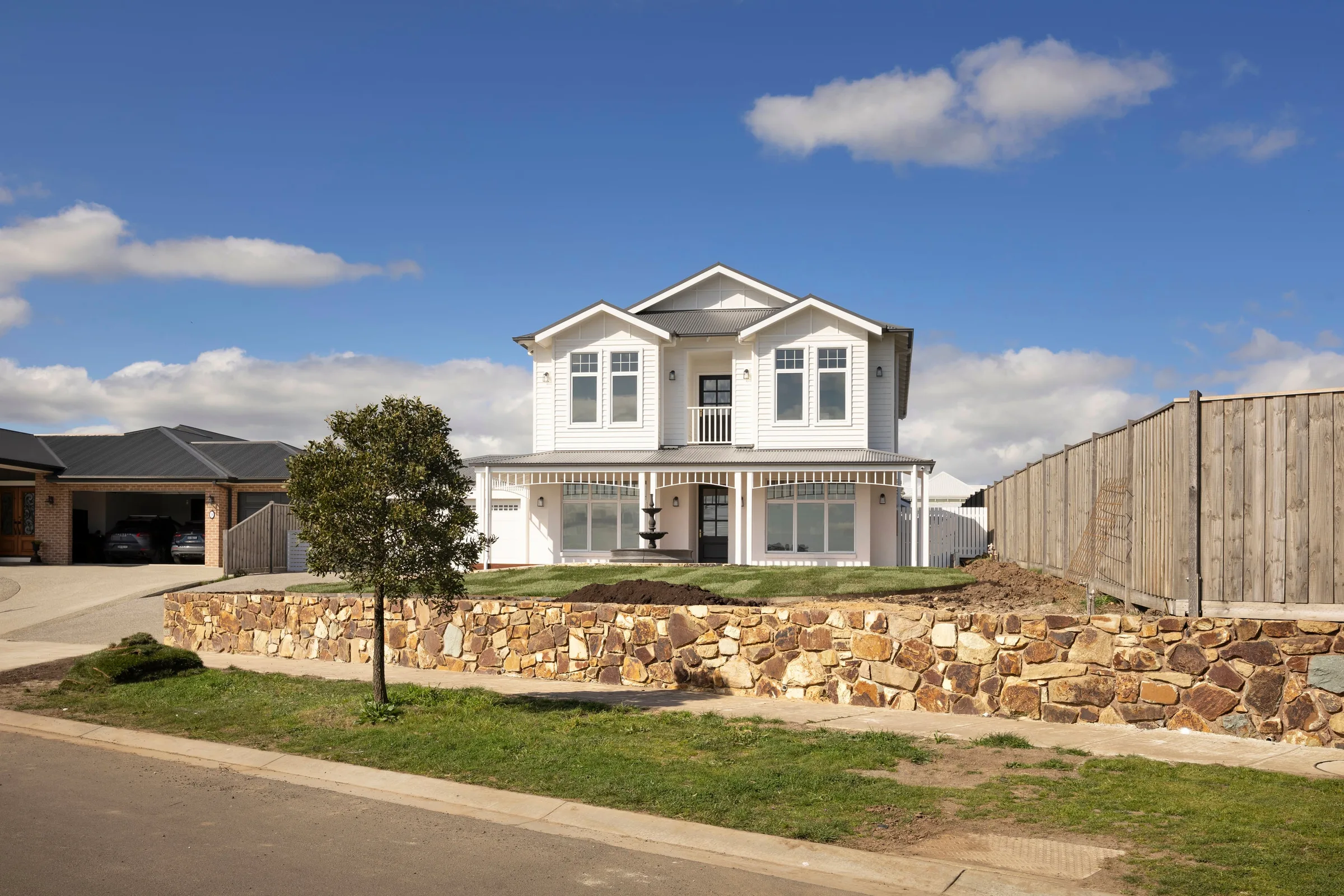 The house from the street, set up behind a stacked-stone retaining wall