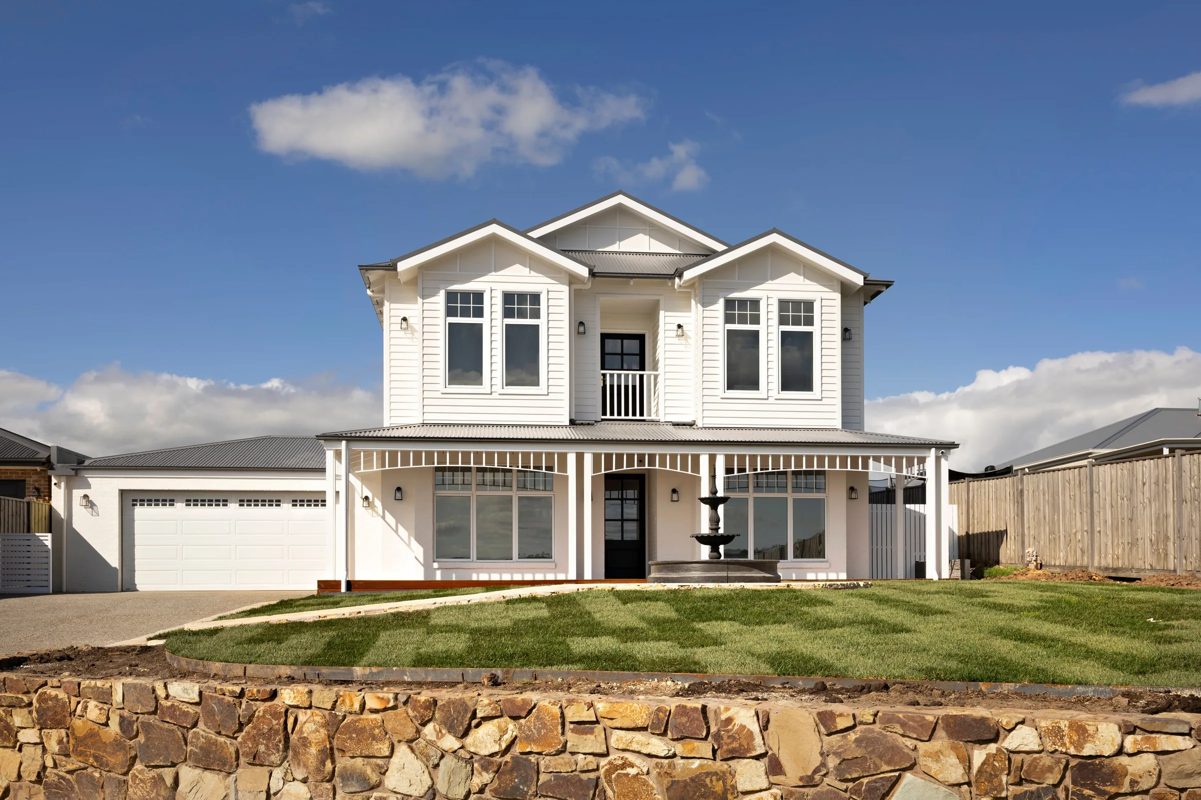Weatherboard facade with twin gables above a dry-stone wall &mdash; Mount Gisborne by Summerfield Homes