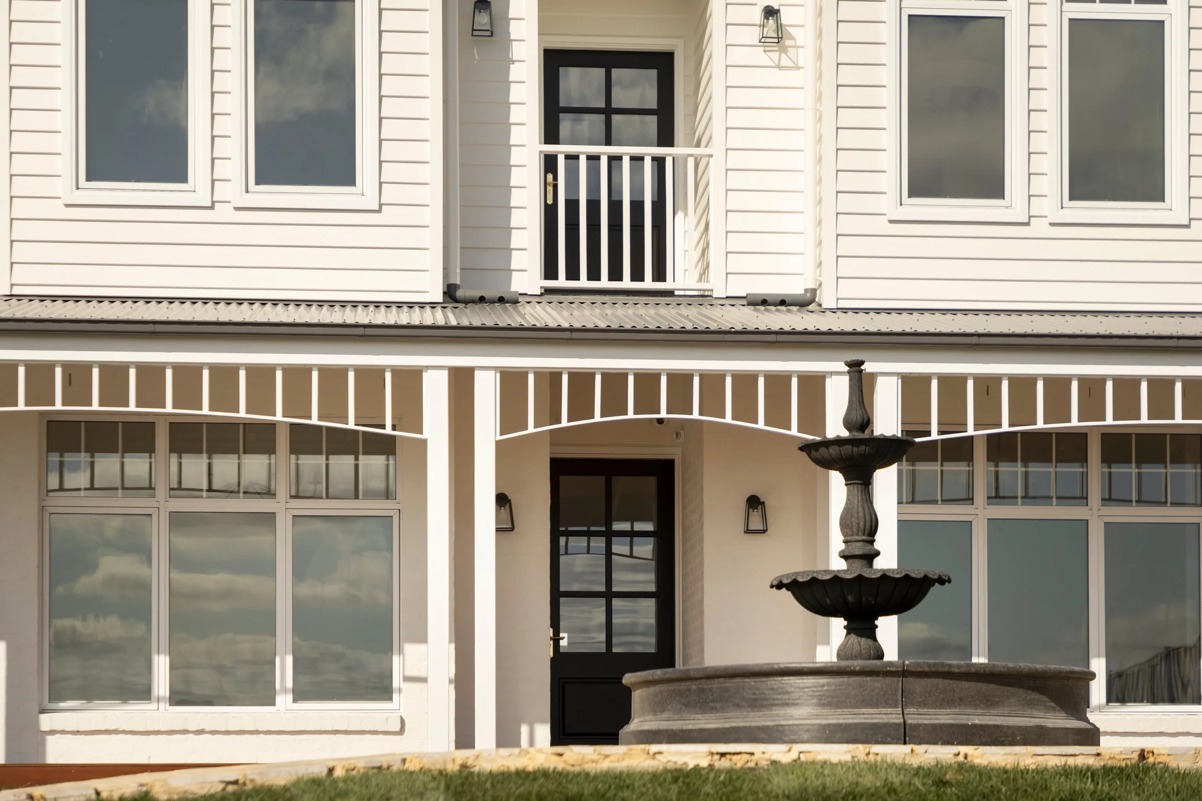 Tiered fountain in front of the black front door and verandah fretwork