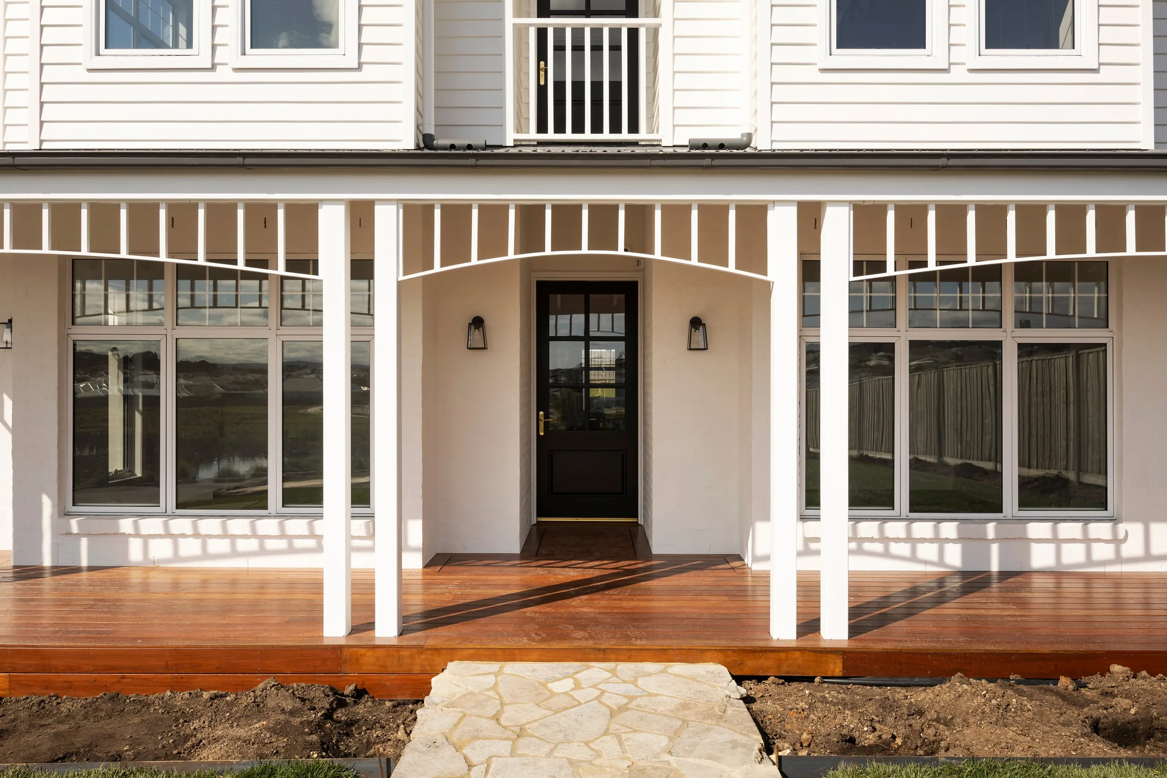 Glazed front door between verandah posts under curved fretwork