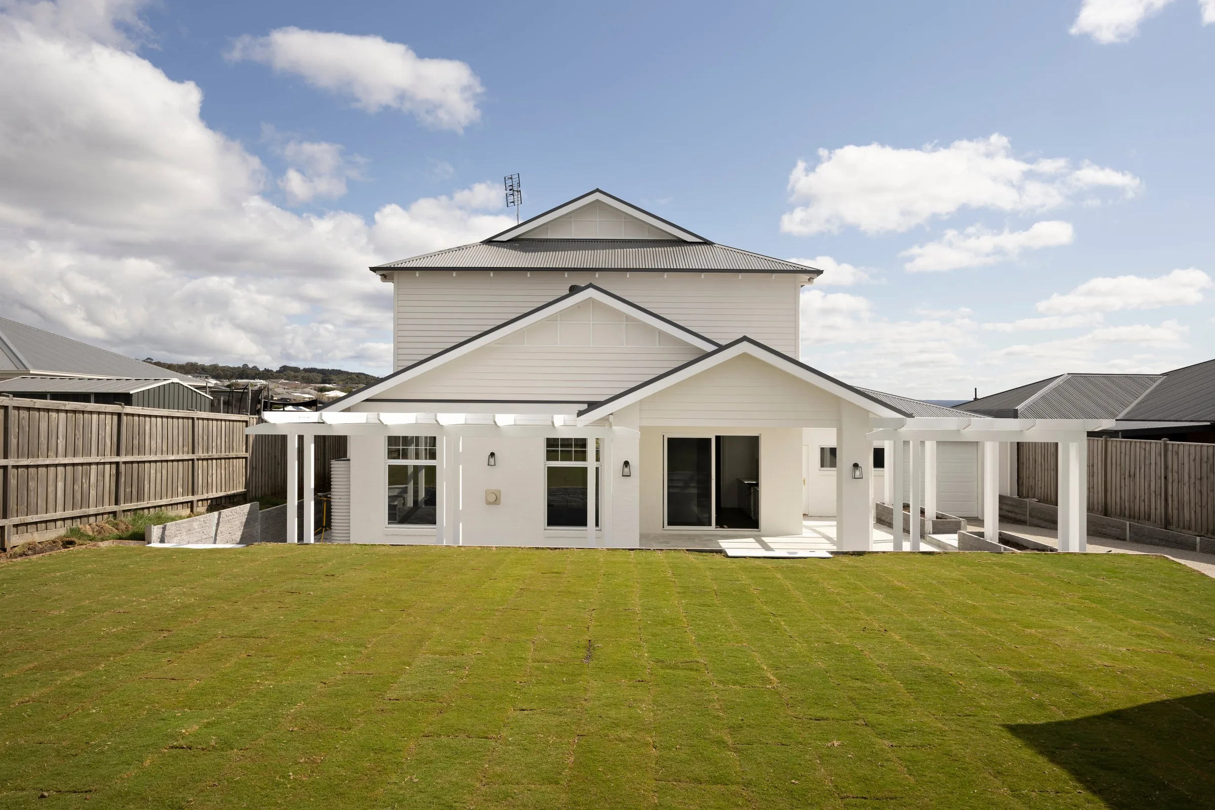 Back lawn running up to the rear of the house and its white pergola