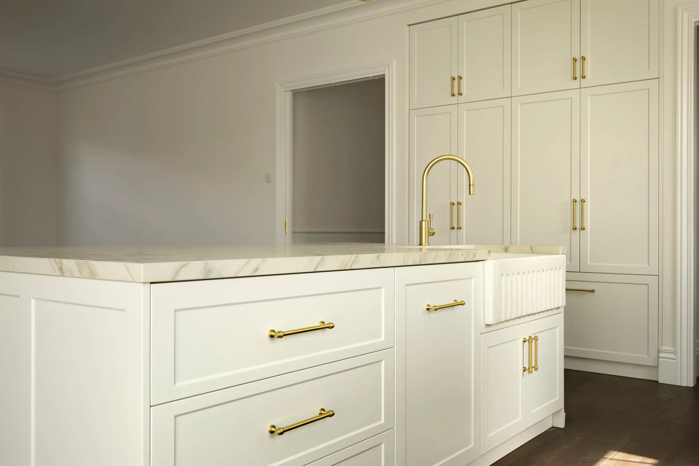 End of the island with brass handles, tall pantry joinery behind