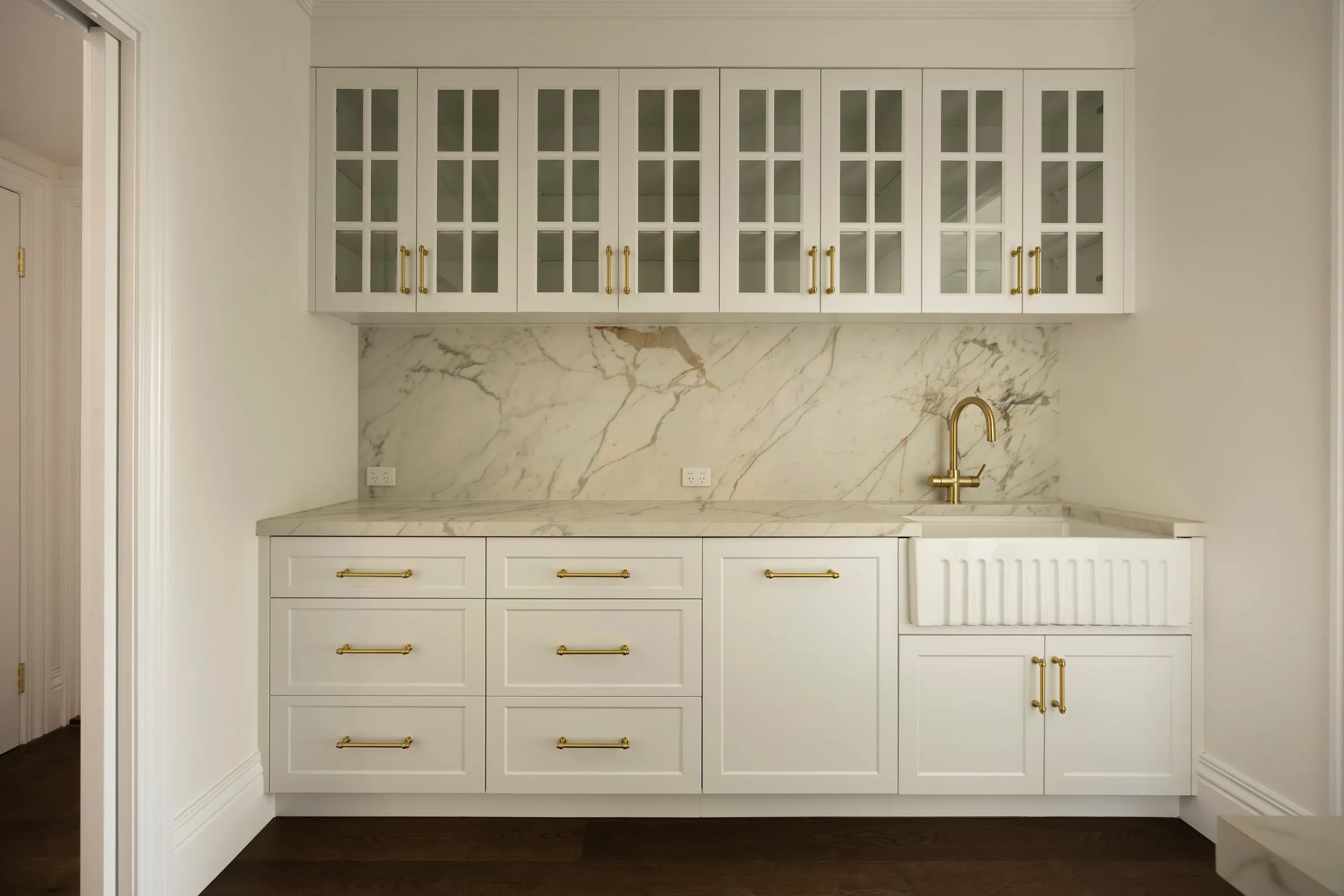 Butler&rsquo;s pantry with glazed upper cabinets and a fluted sink