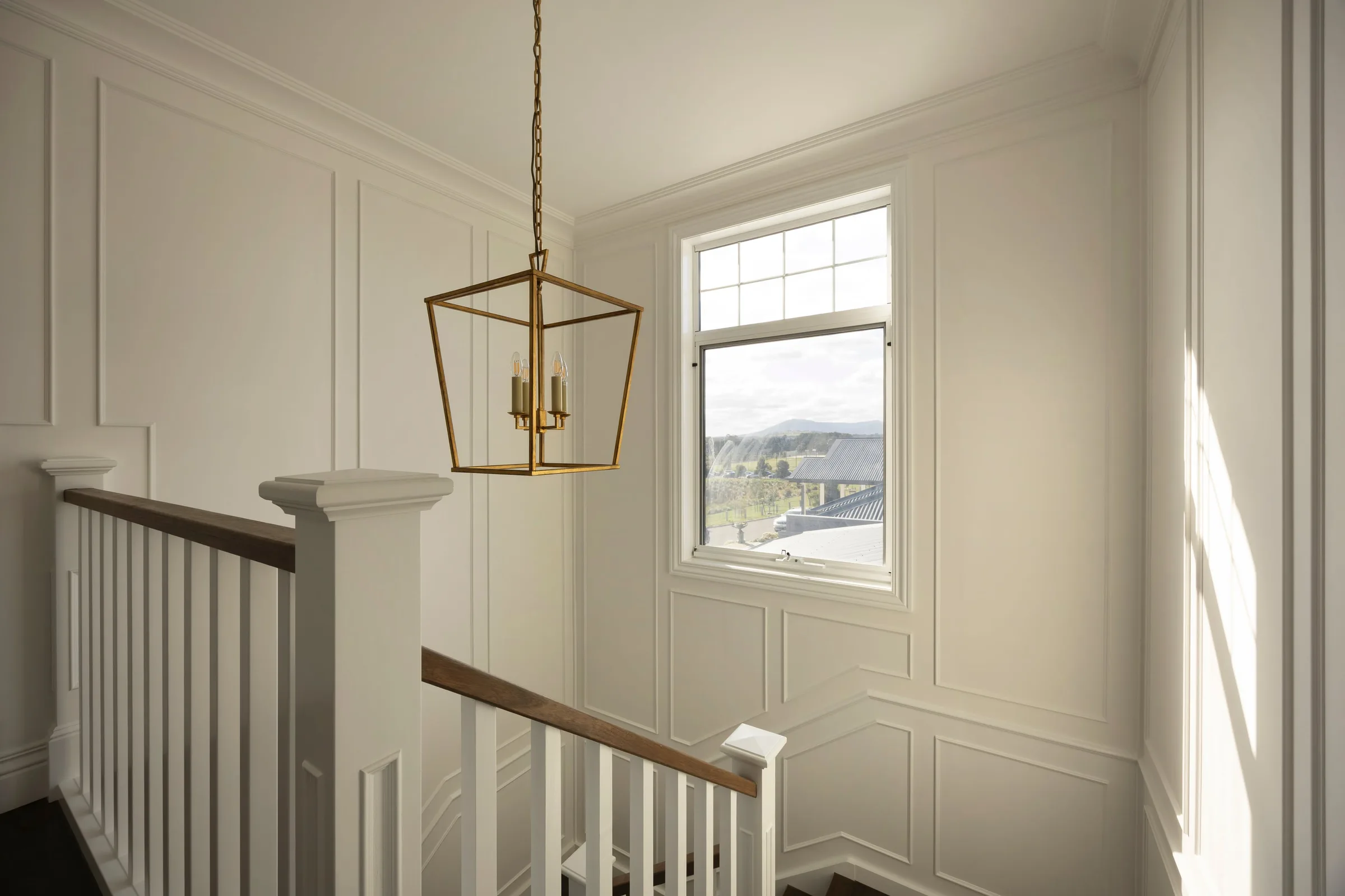 Stair landing with a brass lantern pendant and wall panelling