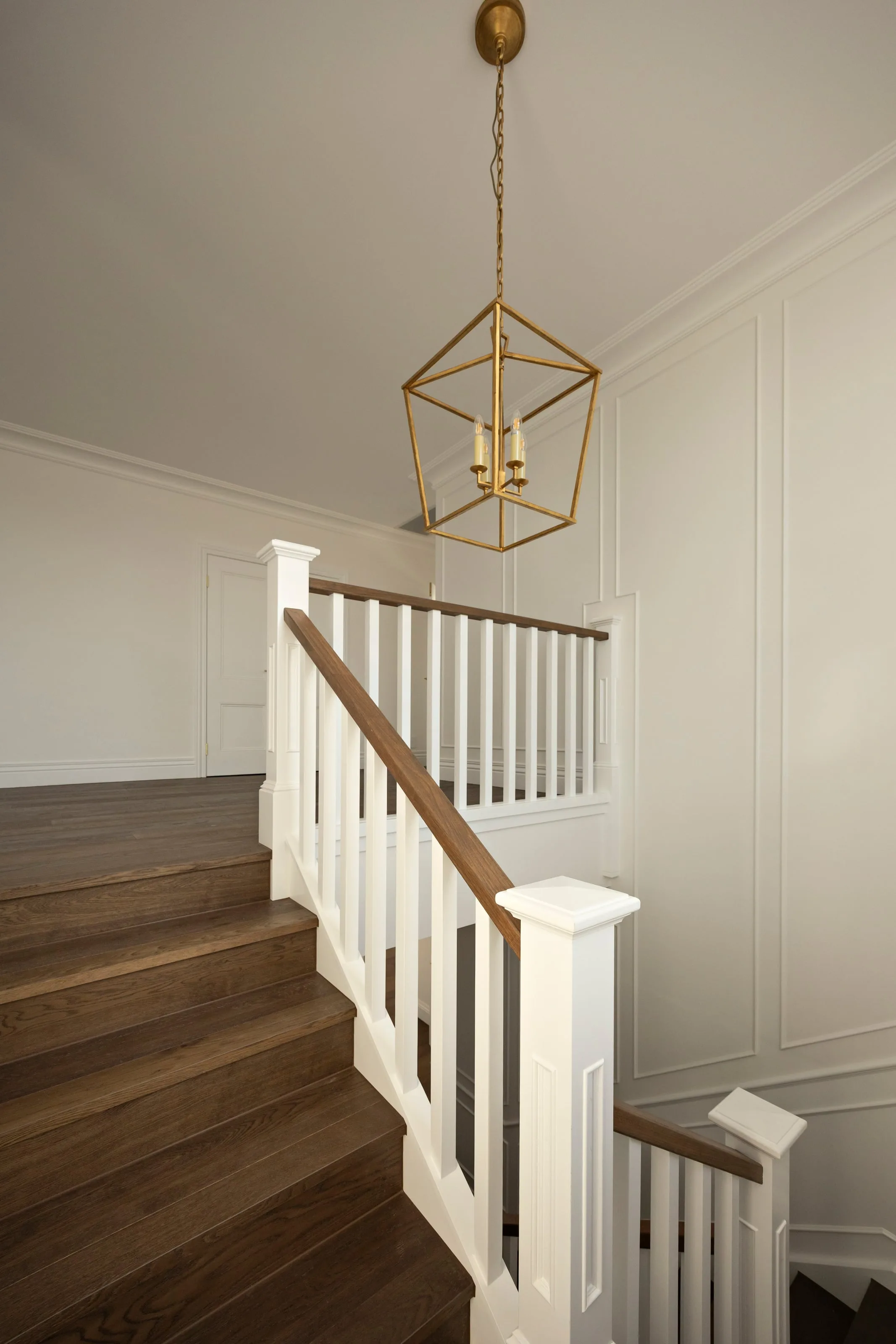 Stairs turning up to the landing under the lantern pendant