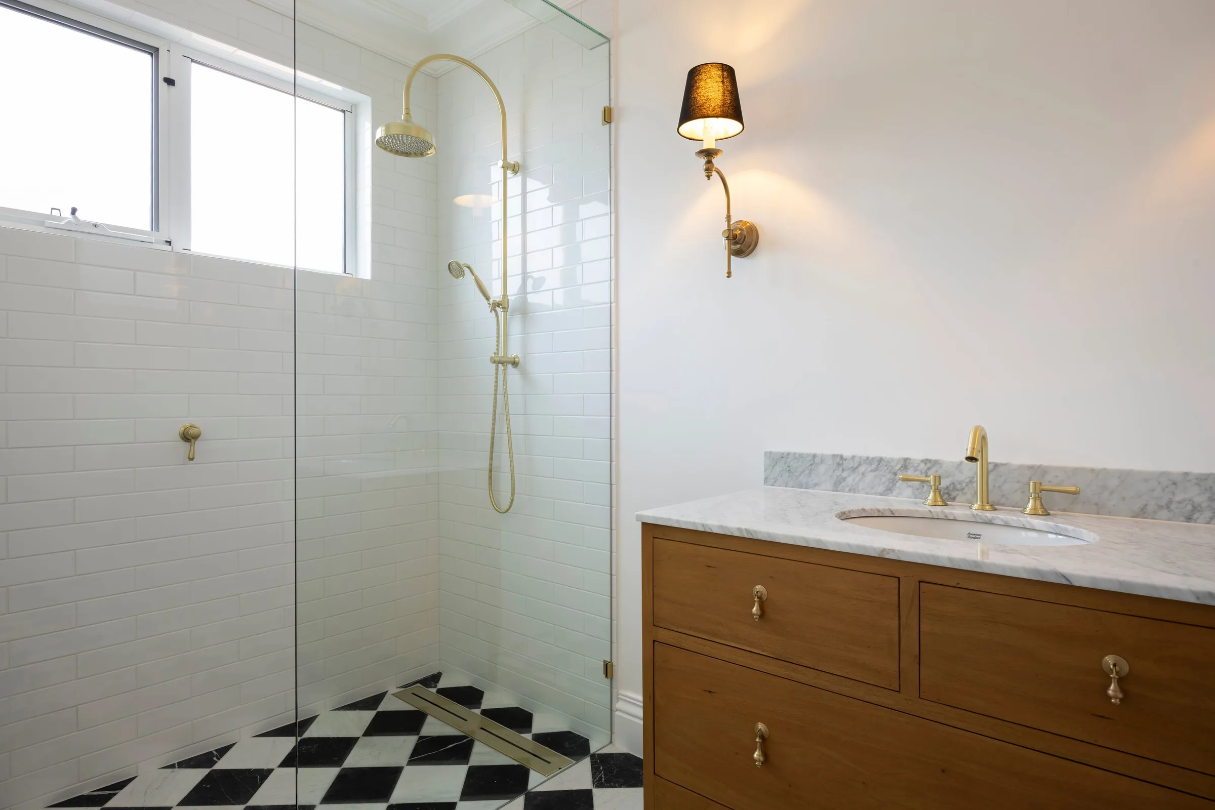 Shower with brass rail set and a timber vanity on checkerboard tiles