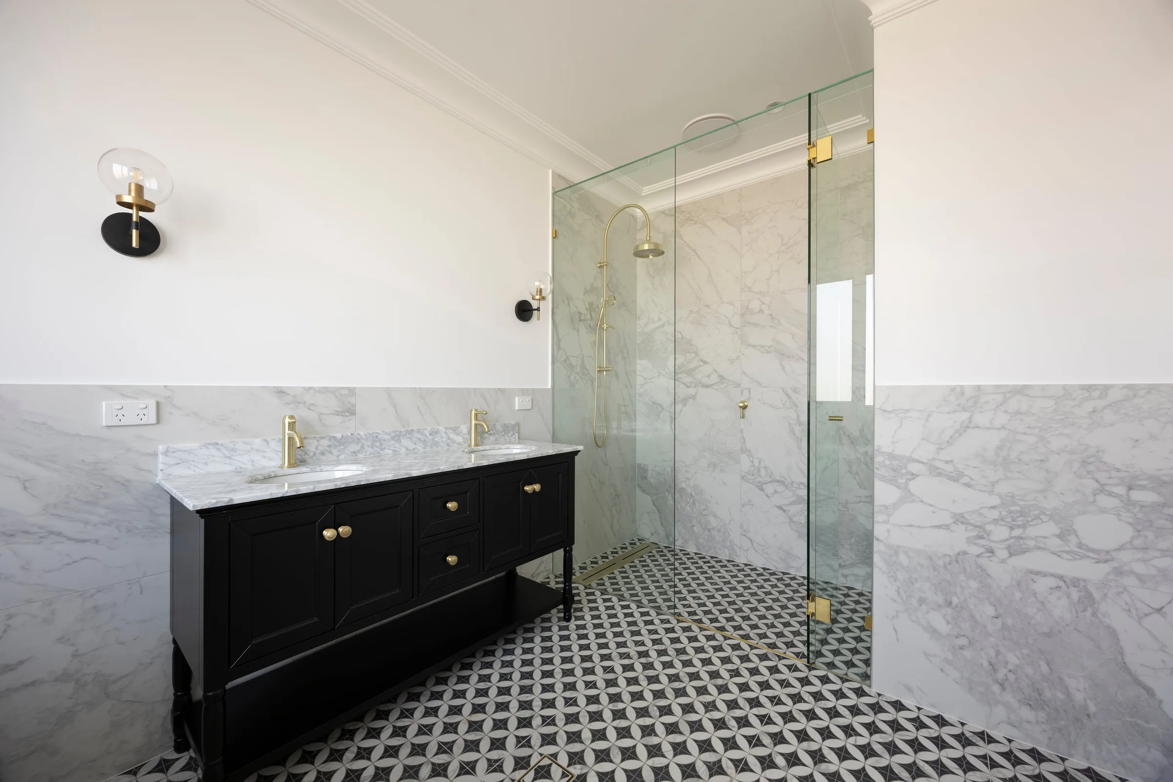 Black vanity and frameless shower against marble-look wall tiles