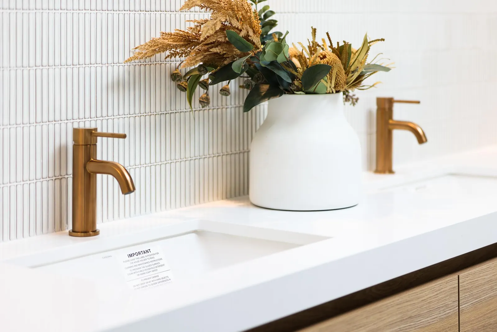 Close view of a brass basin mixer and undermount basin on a white stone vanity