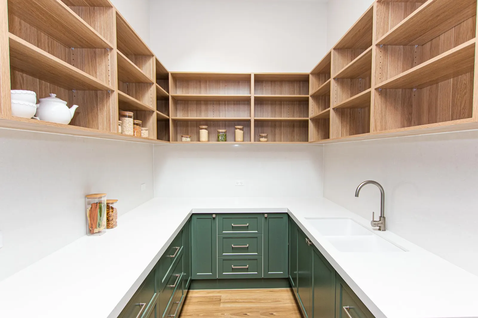 Butler&rsquo;s pantry with timber open shelving, green joinery and an undermount sink