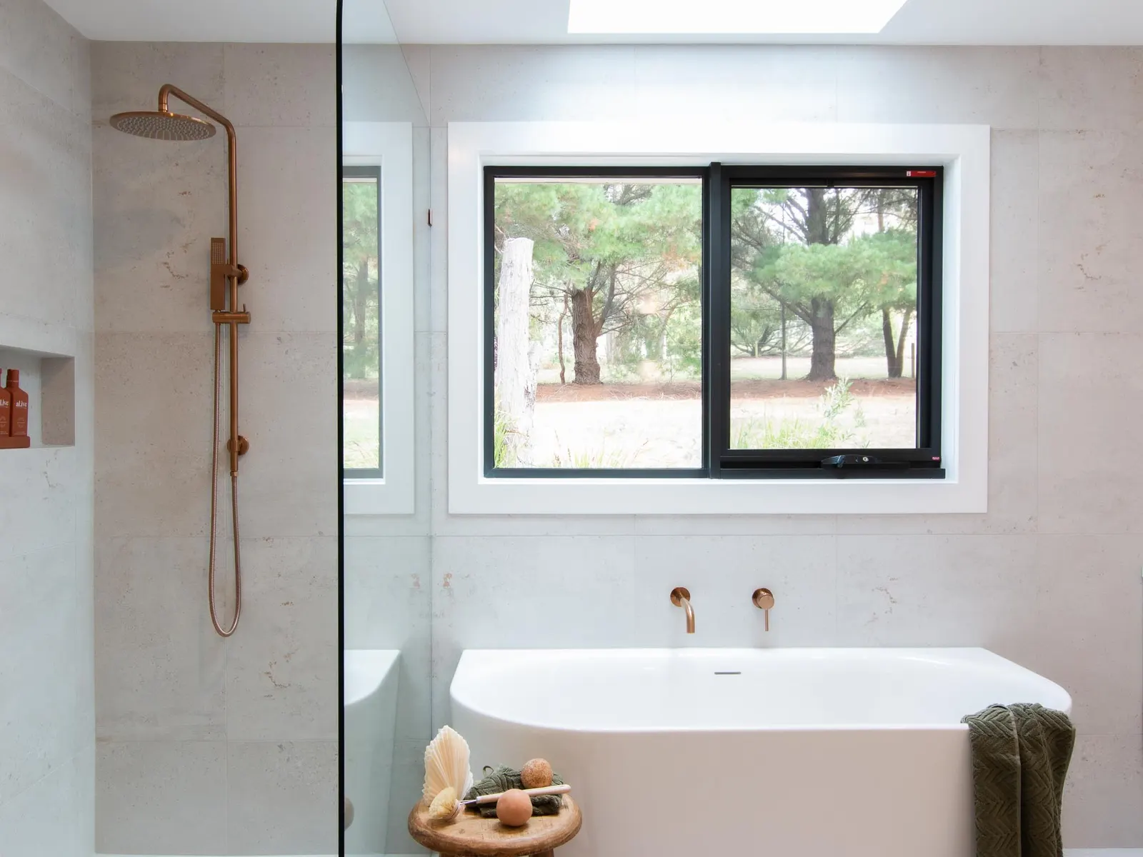 Freestanding bath below a black-framed window with bushland views, Spencer Rd