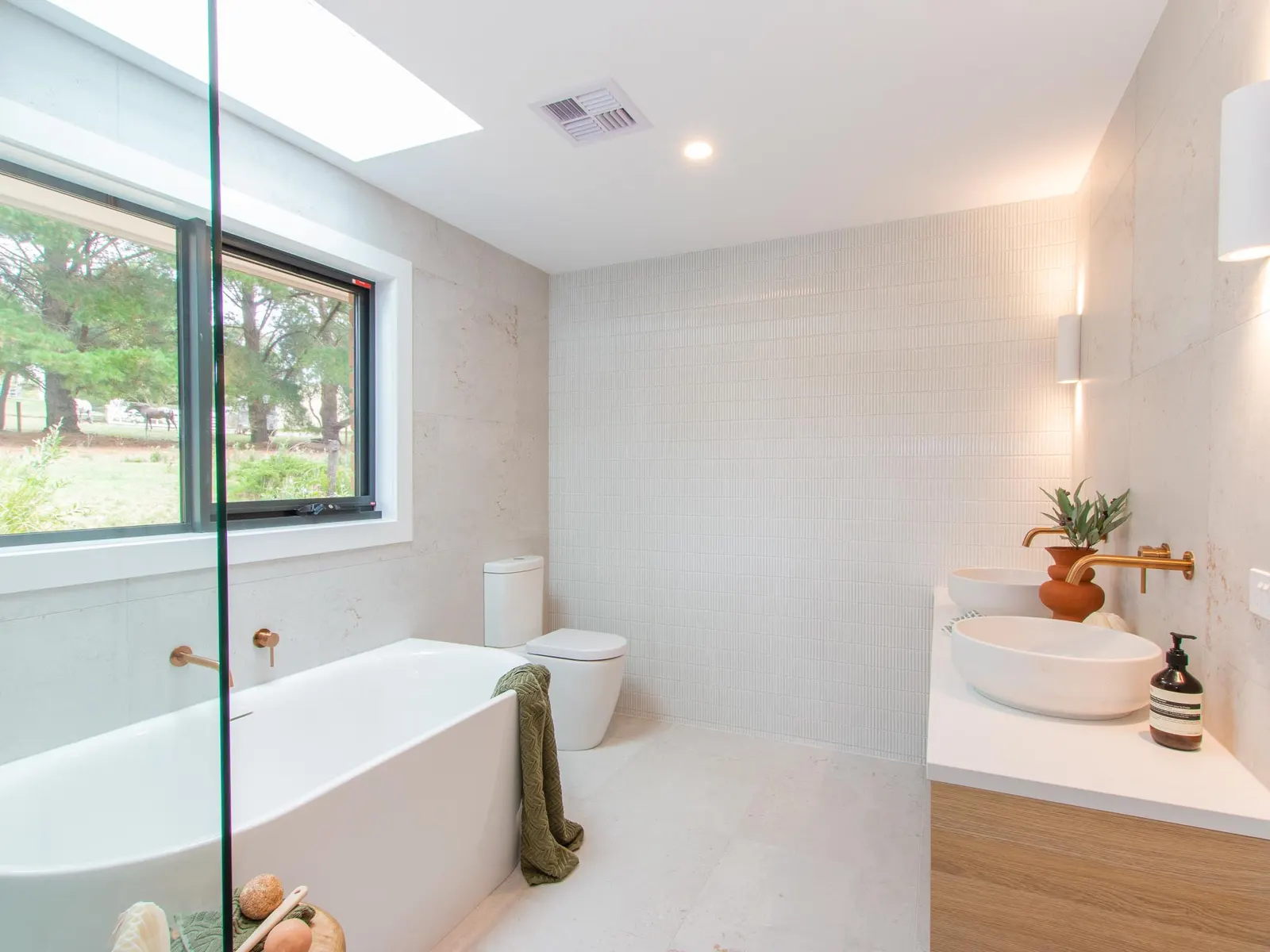 Bathroom with a freestanding bath, skylight and a timber vanity with a vessel basin