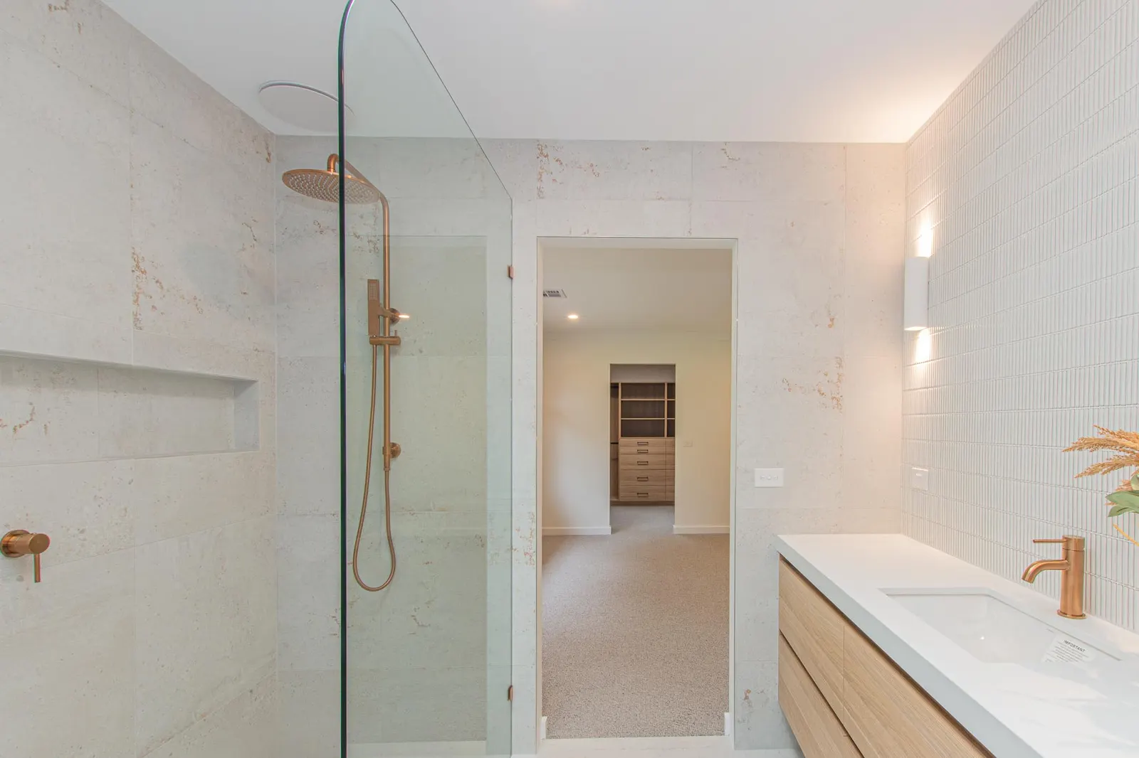 Walk-in shower with brass fittings and a glass screen, opening through to the robe