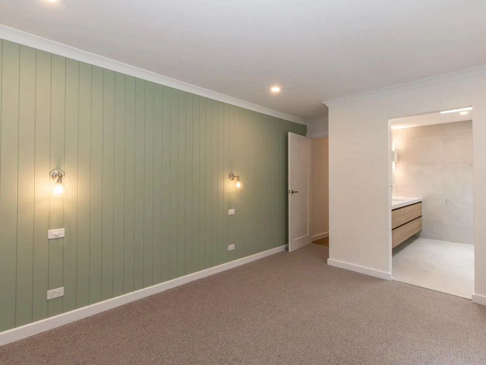 Spencer Rd bedroom with a sage green VJ panelled feature wall and ensuite beyond
