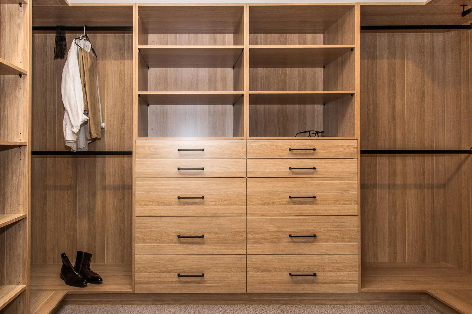 Walk-in robe in timber joinery with hanging rails, open shelving and a bank of drawers