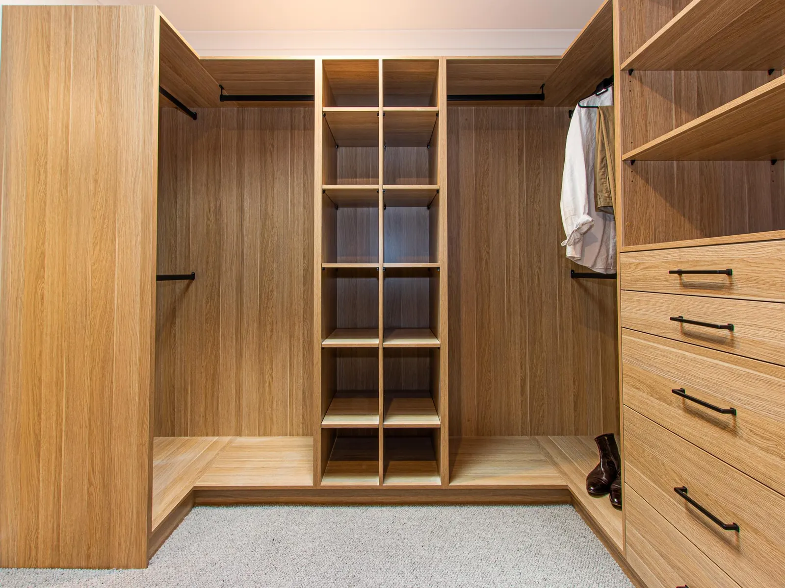 Corner of the walk-in robe with a shelving tower, hanging space and timber drawers
