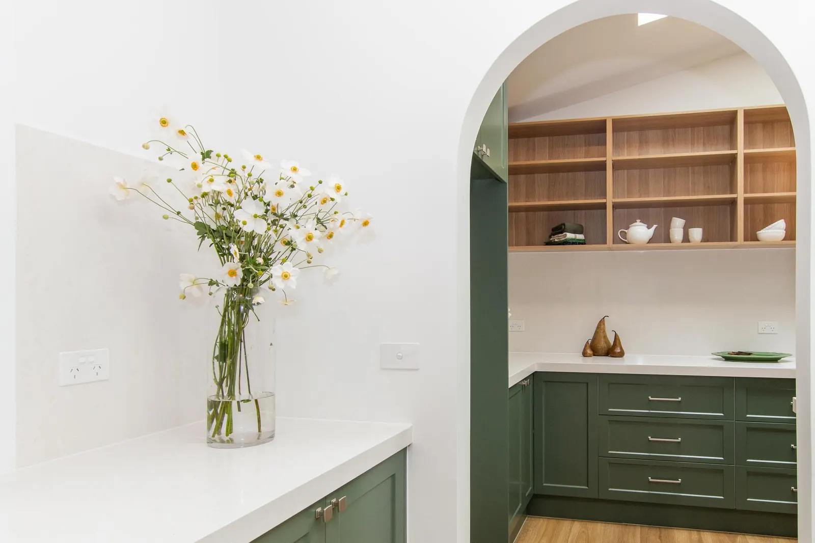 Arched opening framing the butler&rsquo;s pantry, with daisies on the stone benchtop