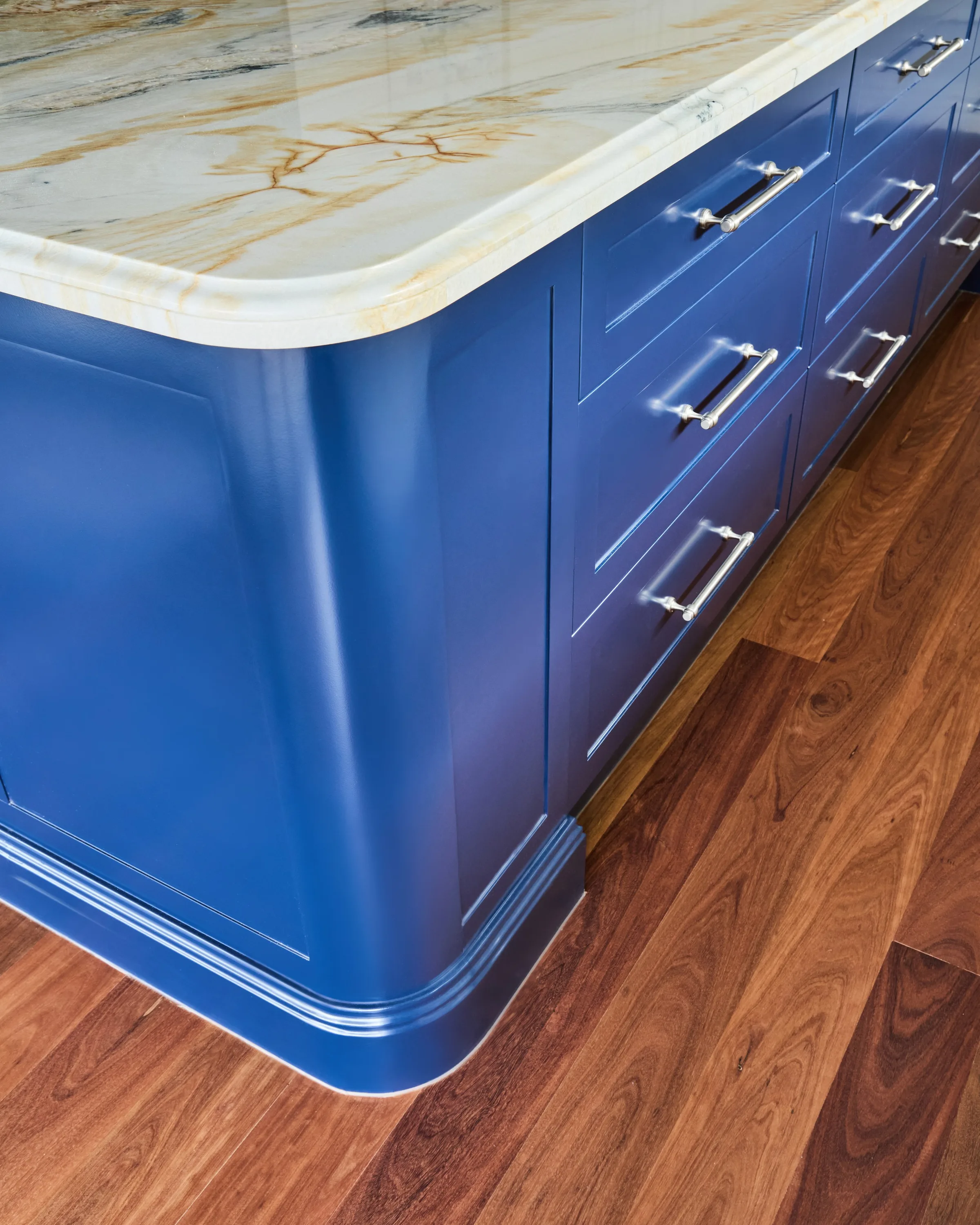Navy shaker island end with chrome cup handles, a moulded plinth and timber flooring