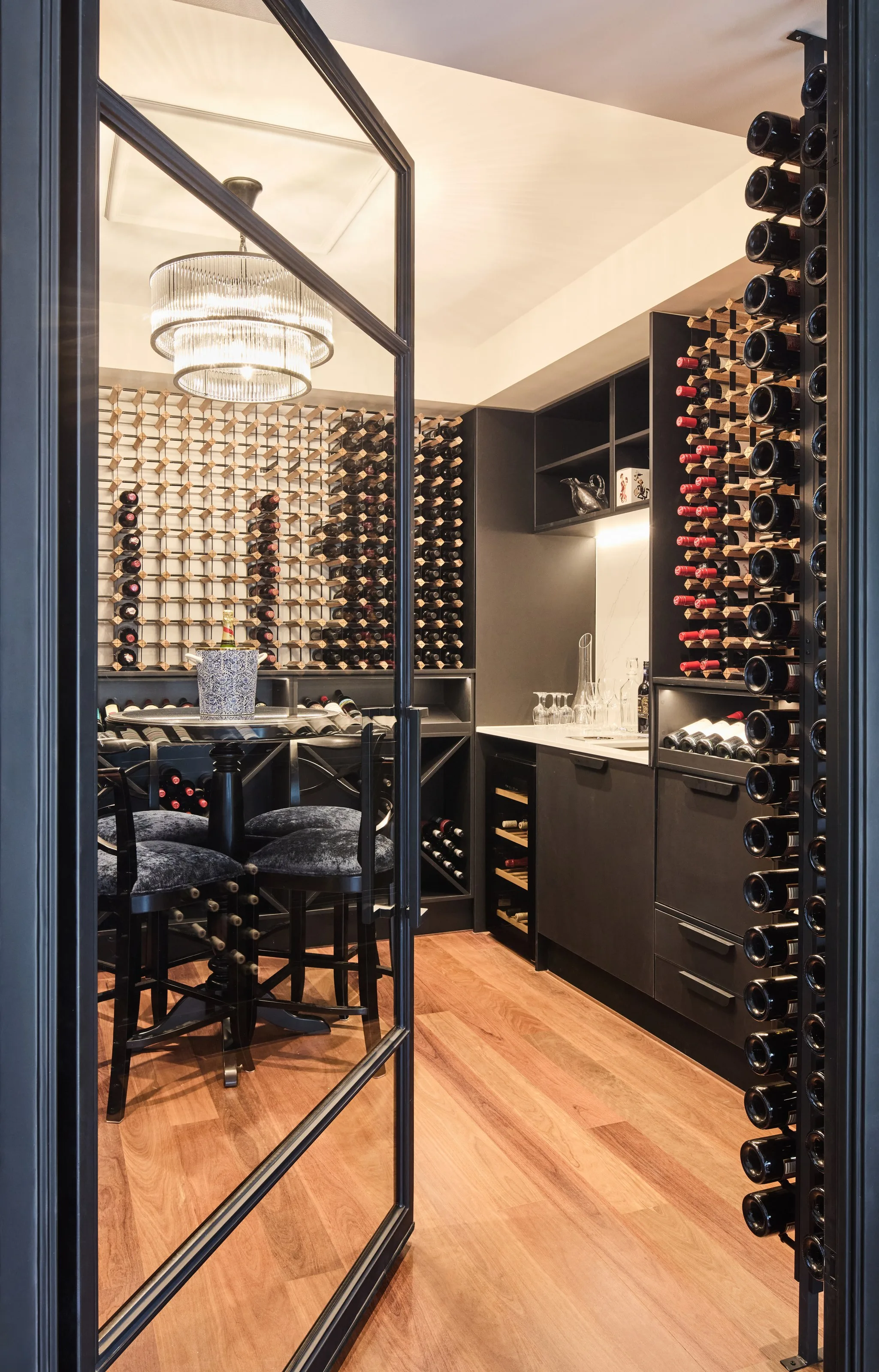 Inside the wine cellar: black joinery, racking to the ceiling and a chandelier over the tasting table